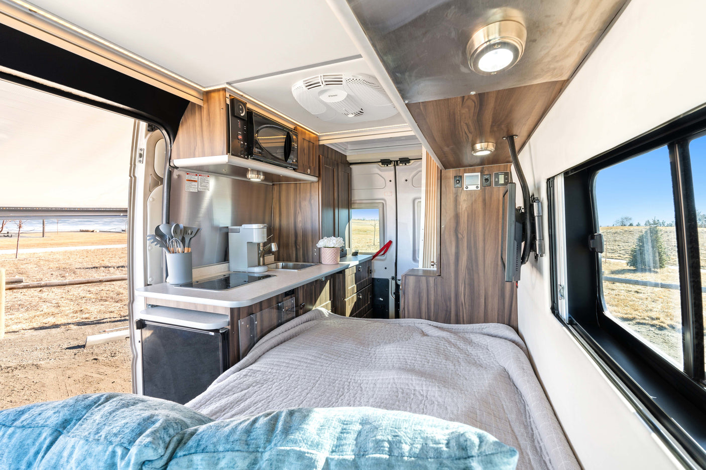 Experience comfort in this cozy RV rental's versatile interior, featuring a compact kitchen, bed, and scenic views.
