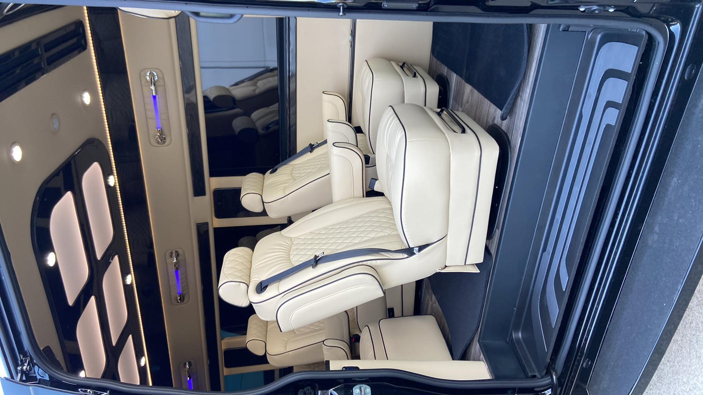 Luxury RV rental interior with plush cream leather seats, black piping, and ambient lighting. Ideal for comfortable travel.
