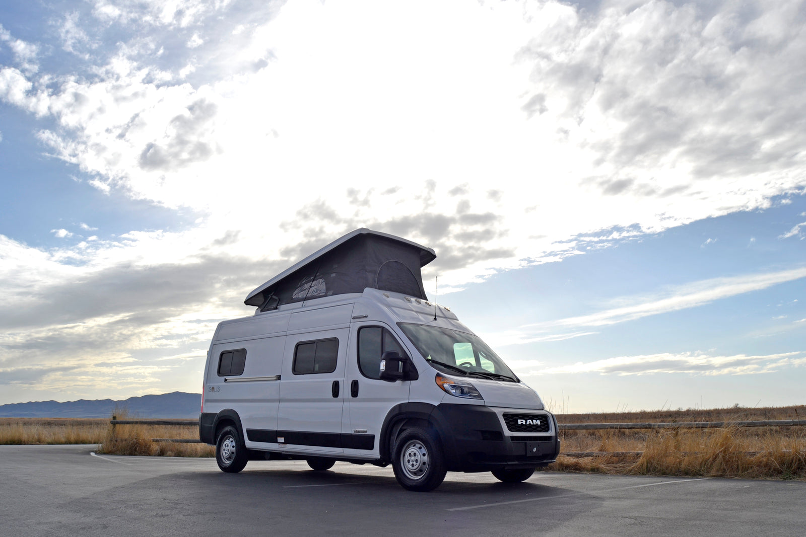 White Solis pop-top rv rental van parked in a scenic outdoor setting, ready for adventure.