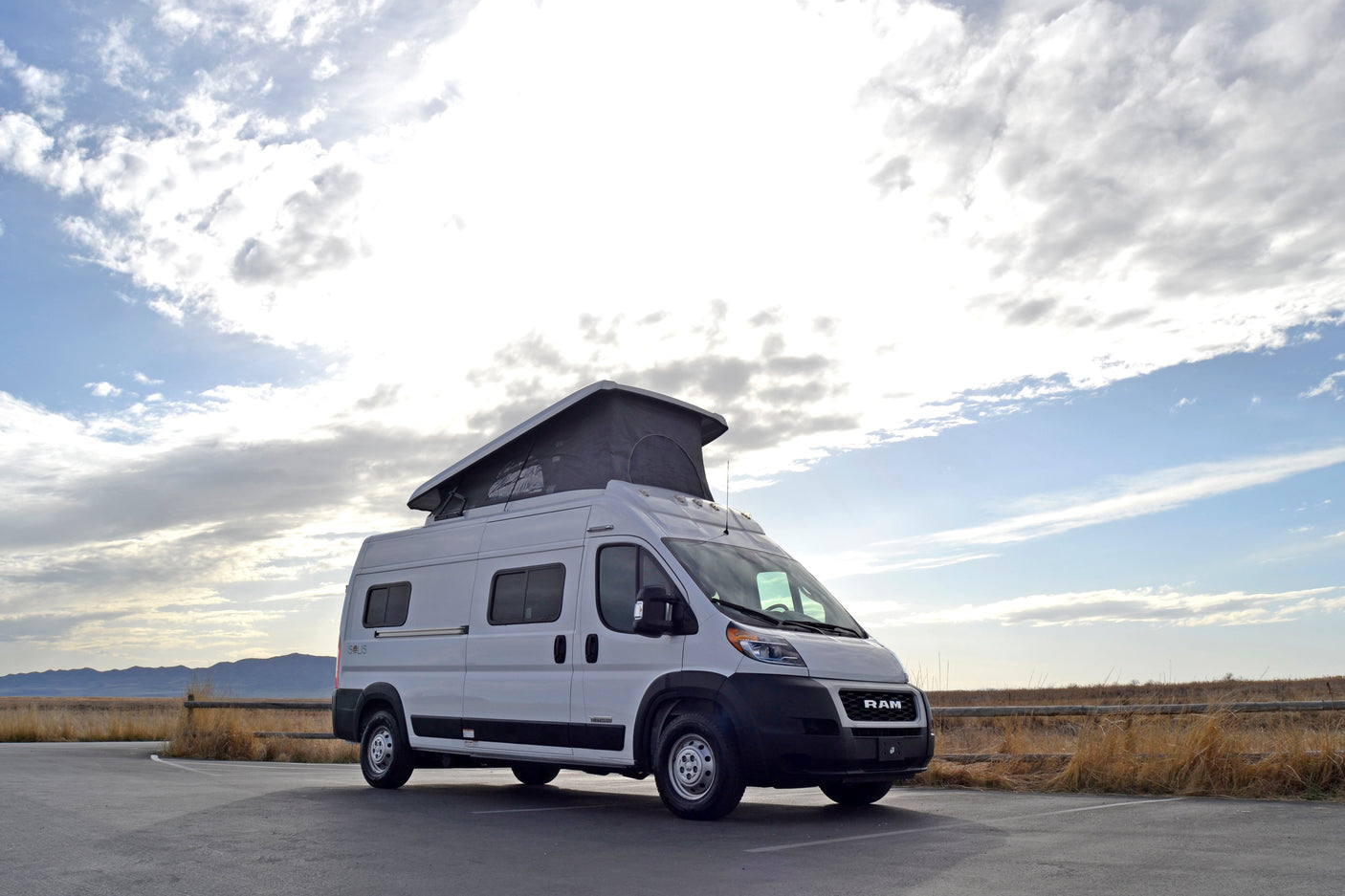 White Solis pop-top rv rental van parked in a scenic outdoor setting, ready for adventure.