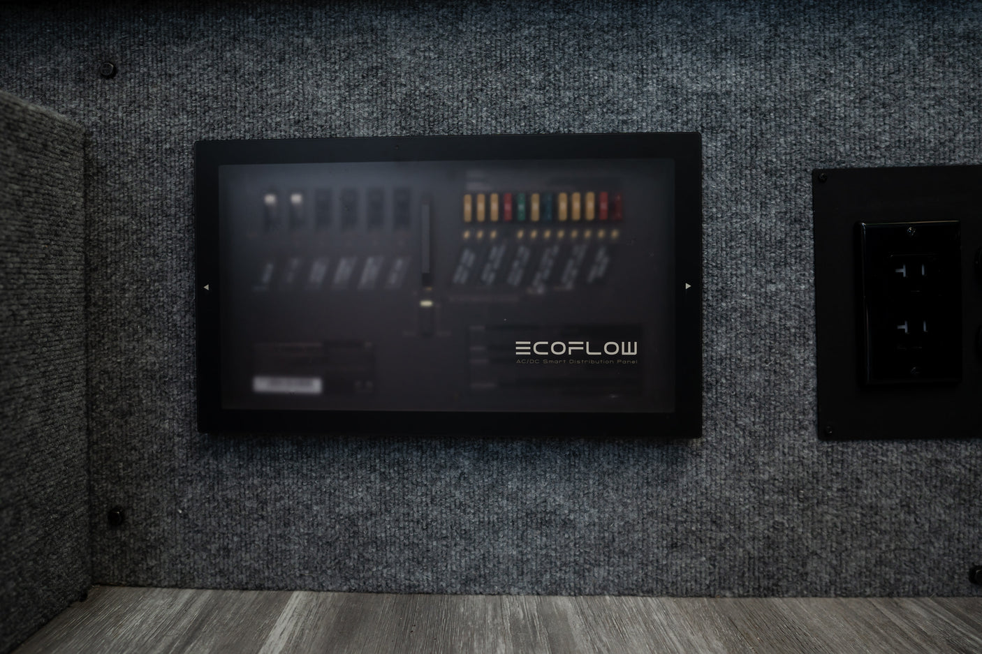 RV rental interior: An Ecoflow AC/DC Smart Distribution Panel for power management, alongside an electrical outlet.