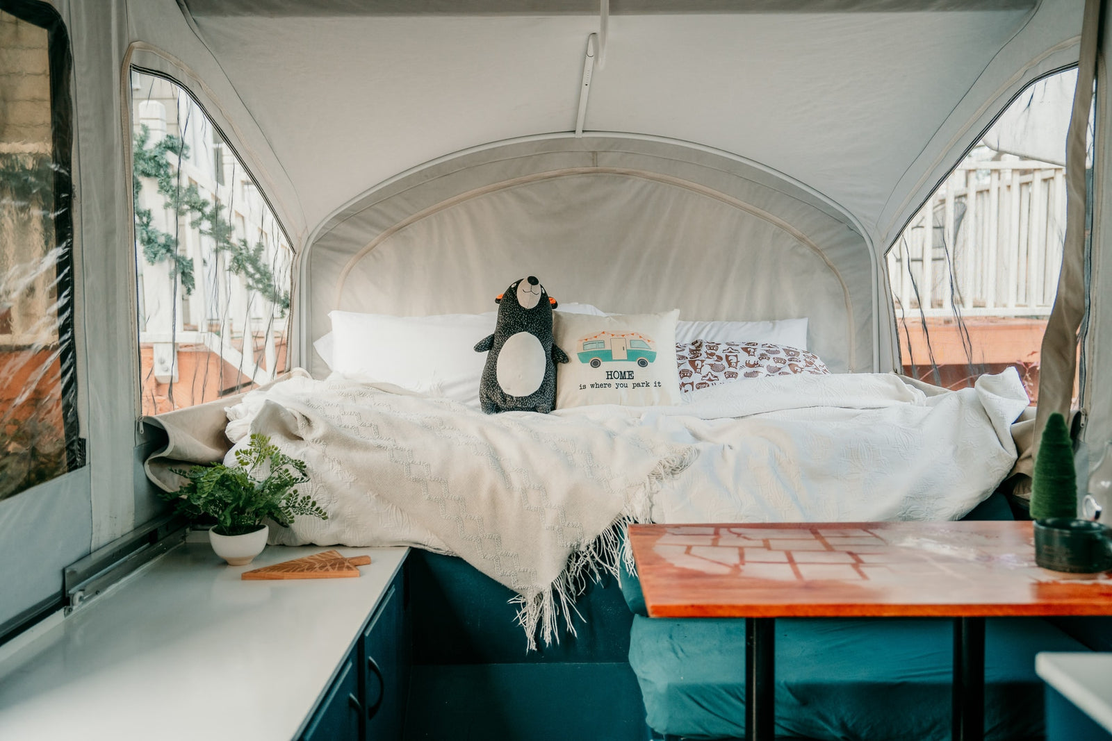 Experience comfort in this RV rental! Enjoy a cozy bed with a "HOME is where you park it" pillow and charming decor.
