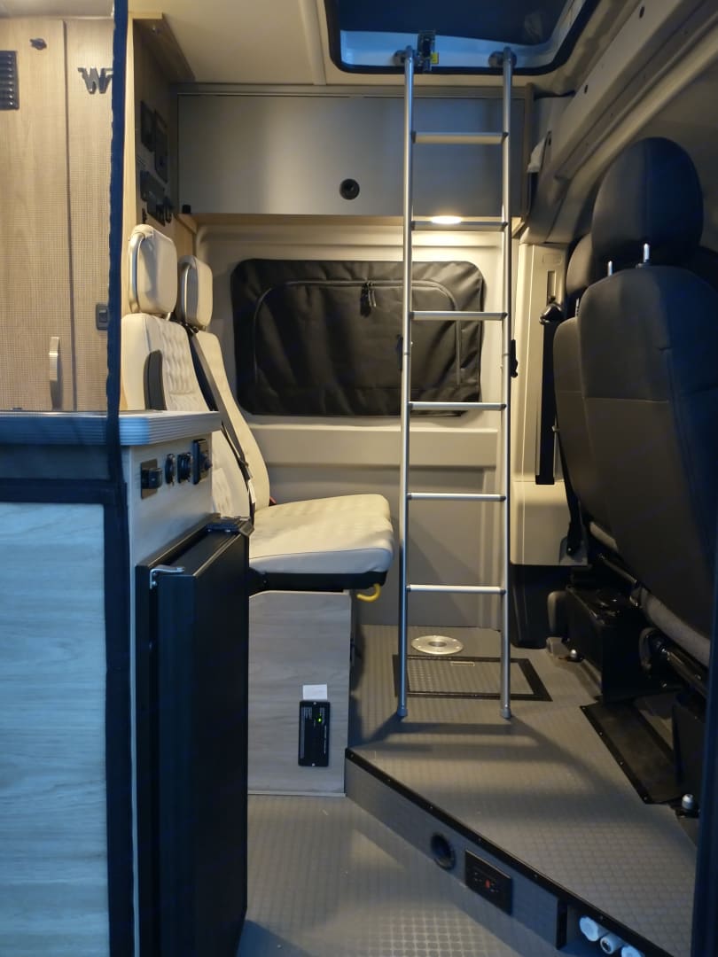 offering stunning desert views.|RV rental comfort: Pop-top camper bed with a beautiful lakeside view