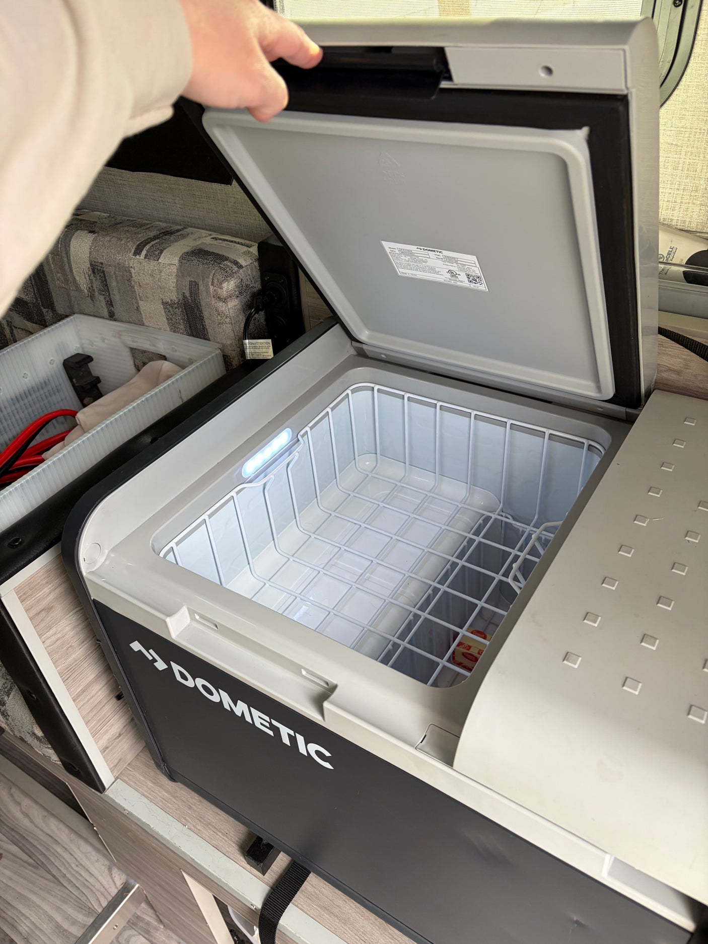 This Dometic portable fridge/cooler in an rv rental is open, showing its lighted interior and storage basket.