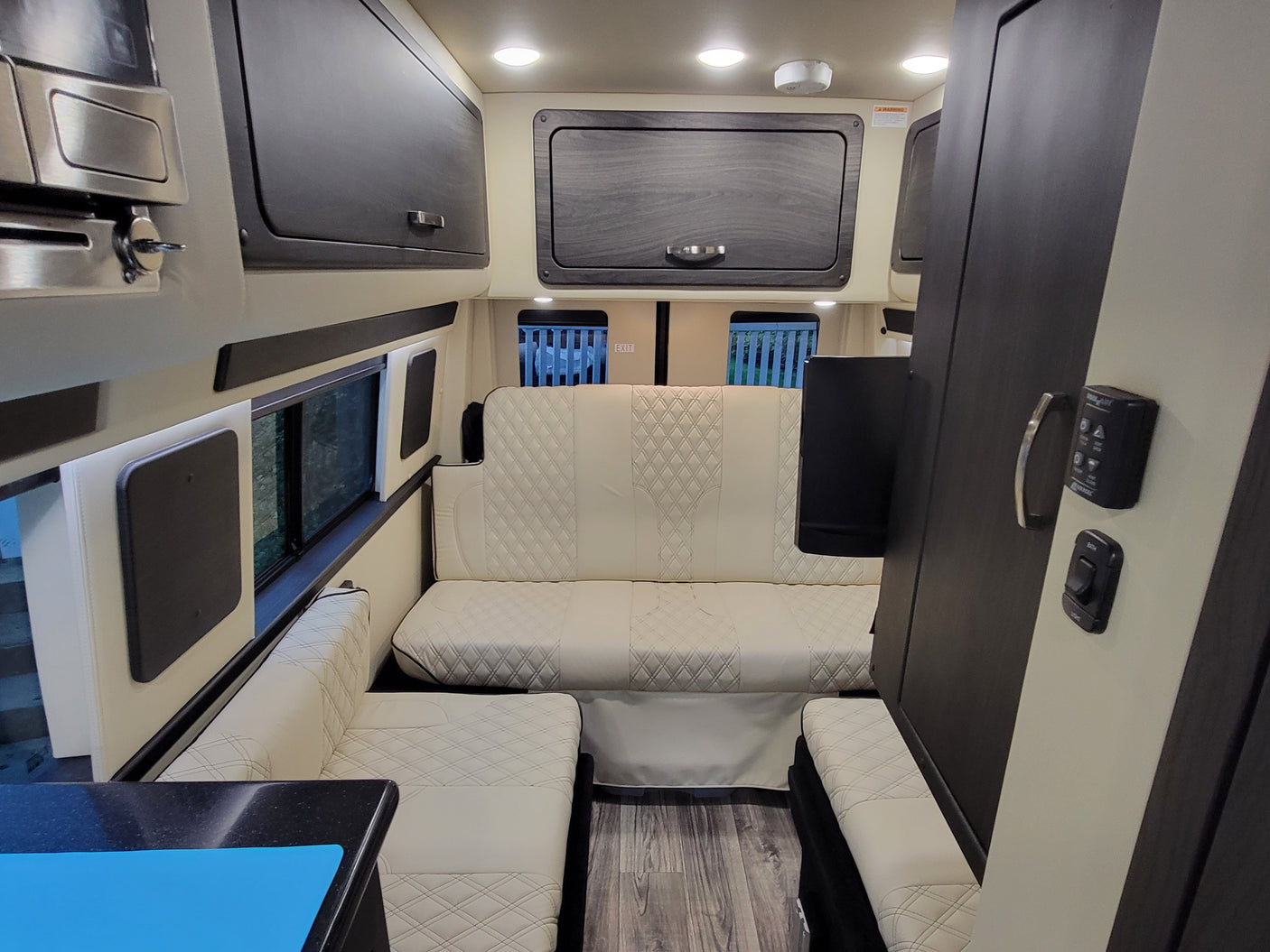 Modern RV rental interior with cream quilted seating, dark cabinets, and essential living amenities.
