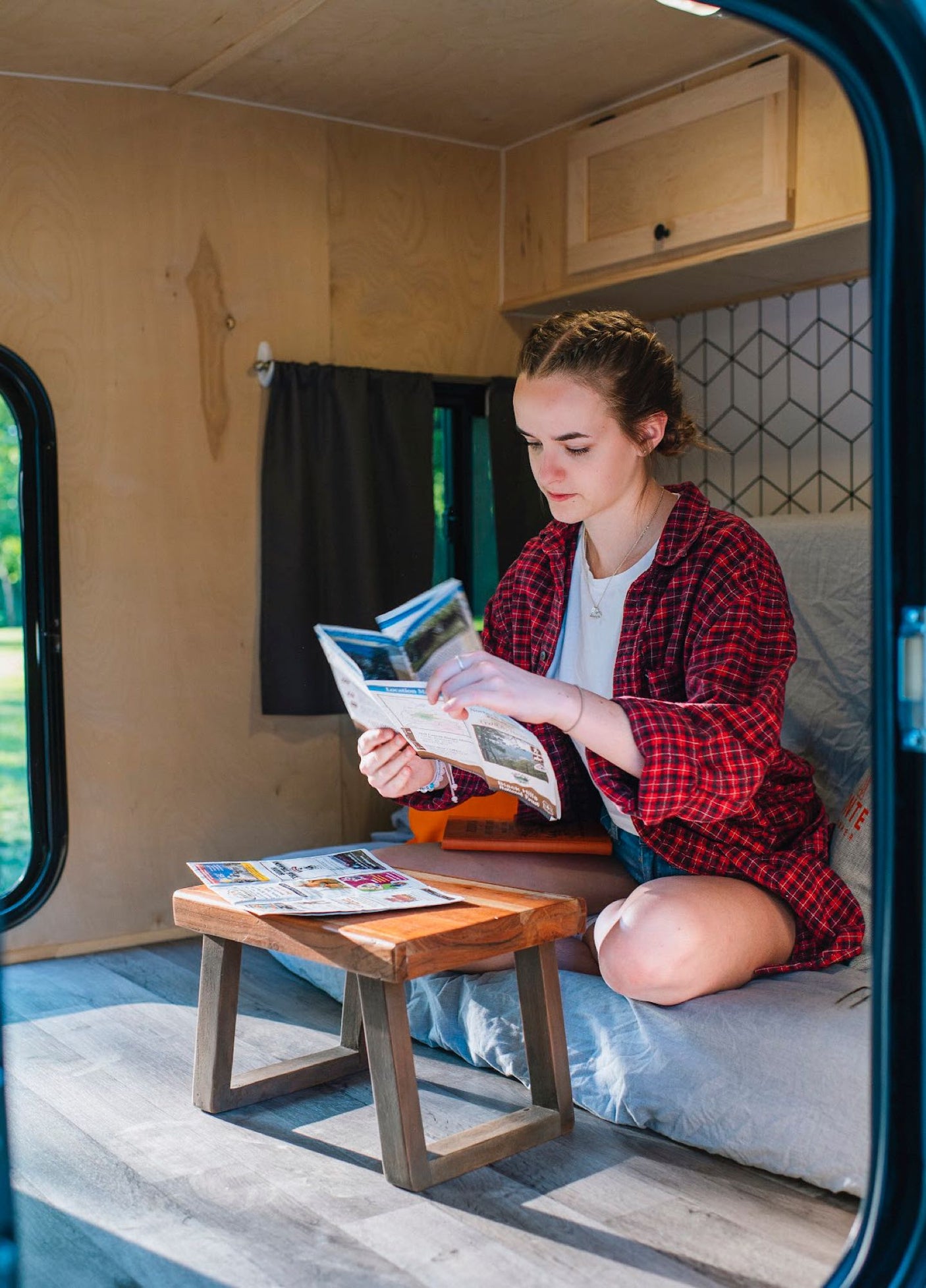door open revealing a comfortable bed & modern patterned interior.|Relaxing RV rental interior: a cozy bed with decorative pillows