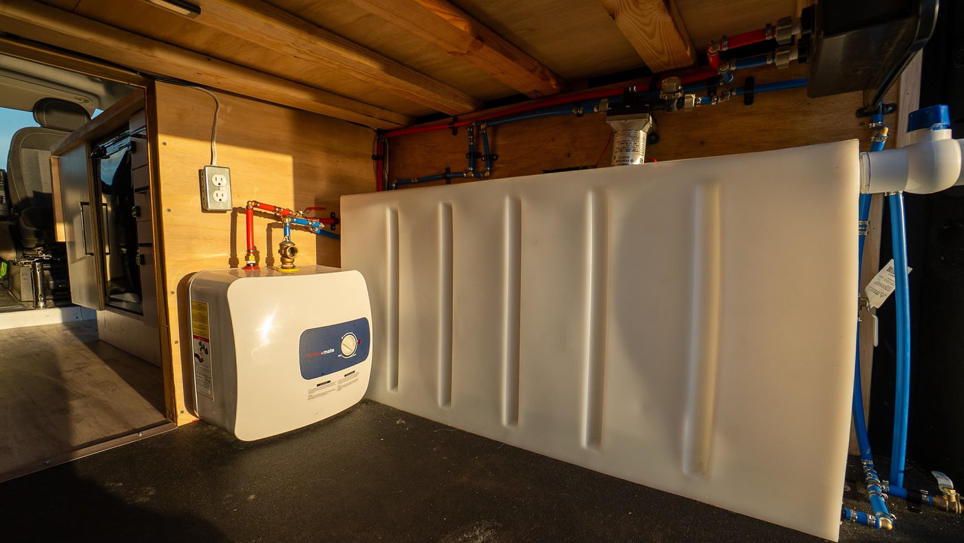 Inside an RV rental, a water heater, tank, and extensive plumbing provide fresh water and hot showers on the road. — photo 13