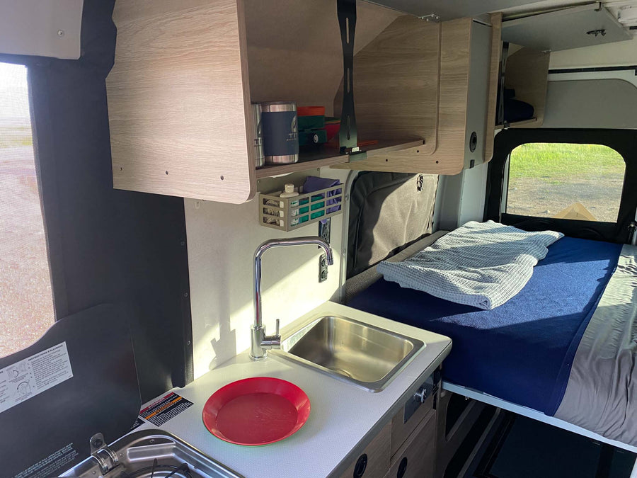 bathed in golden light under cloudy skies.|Inside an RV rental: compact kitchen with sink