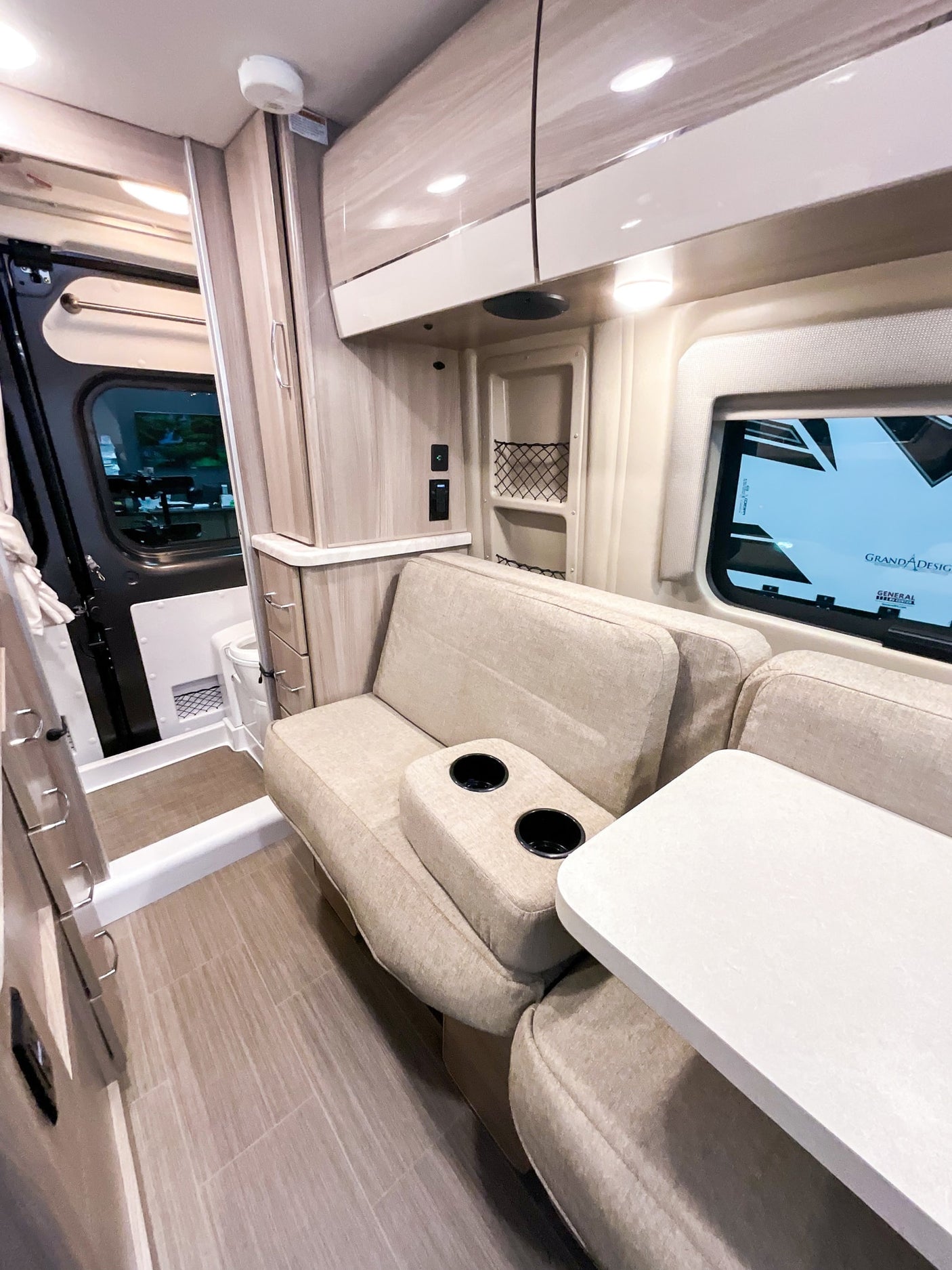 Bright RV rental interior features light wood cabinets, a comfy dinette with cup holders, and a white tabletop.