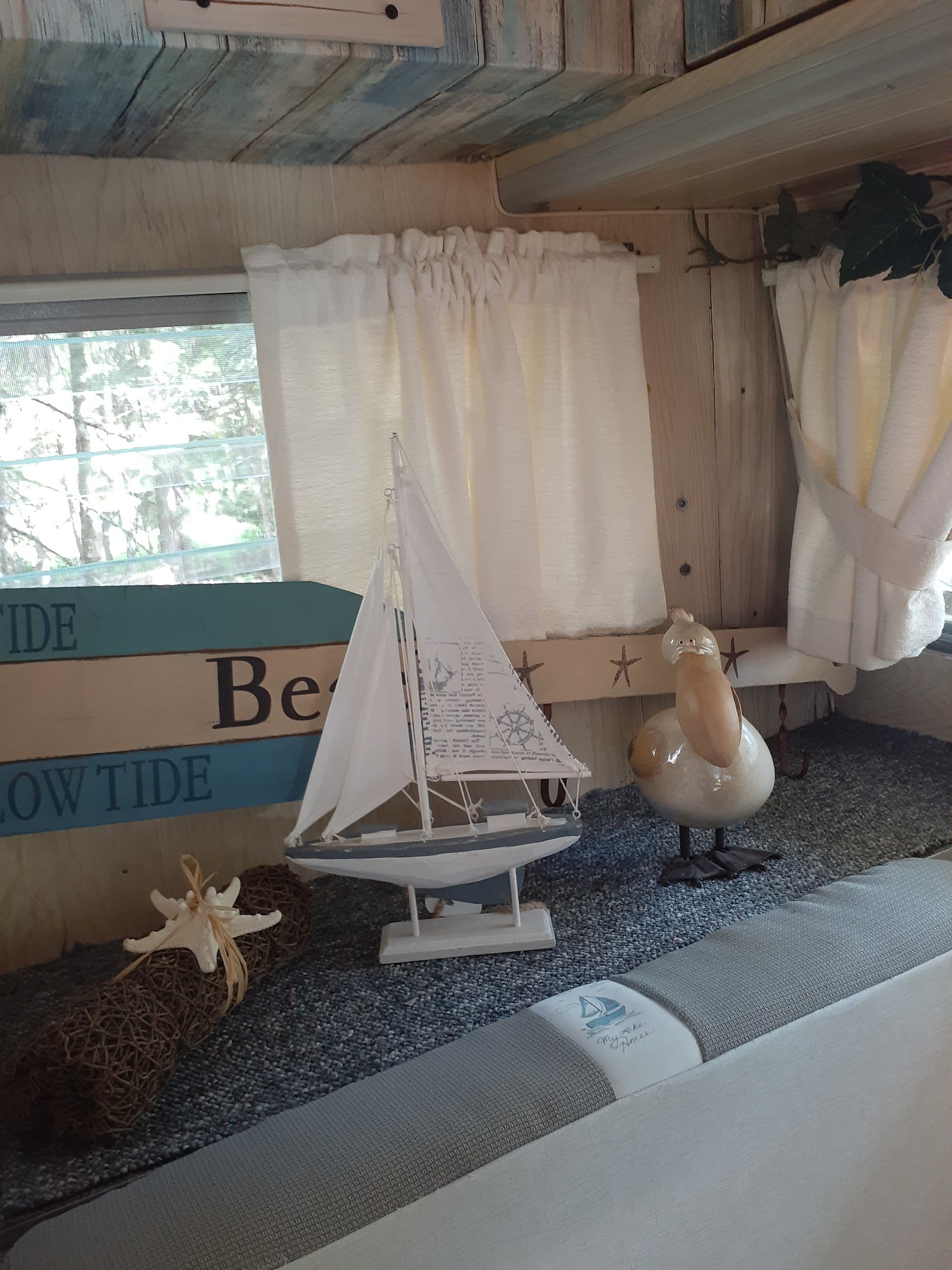 Cozy RV rental interior with beach-themed decor: sailboat, pelican, and starfish accents.