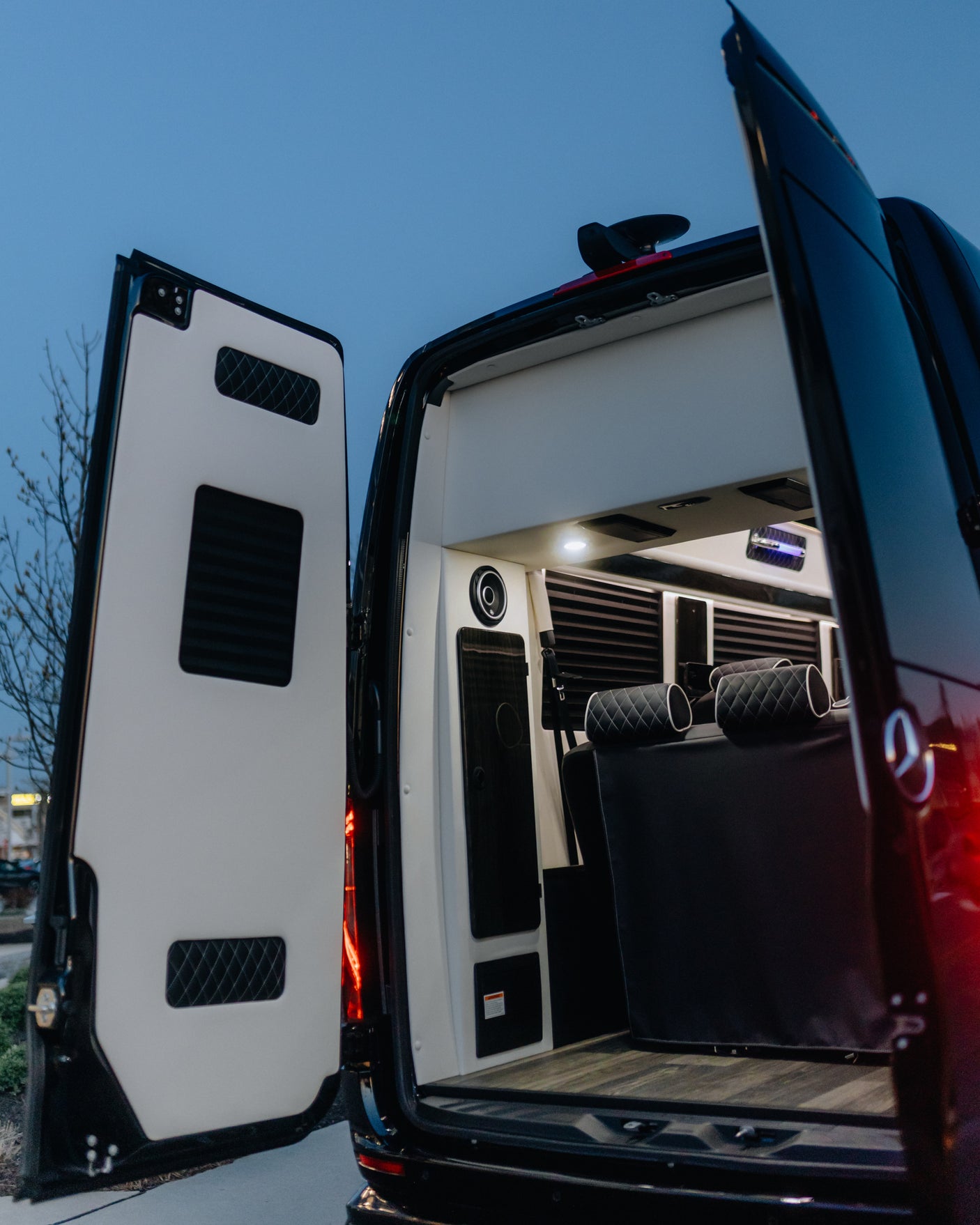Open rear of a luxury Mercedes-Benz Sprinter van for RV rental, showing custom interior, quilted seats & ambient lighting.