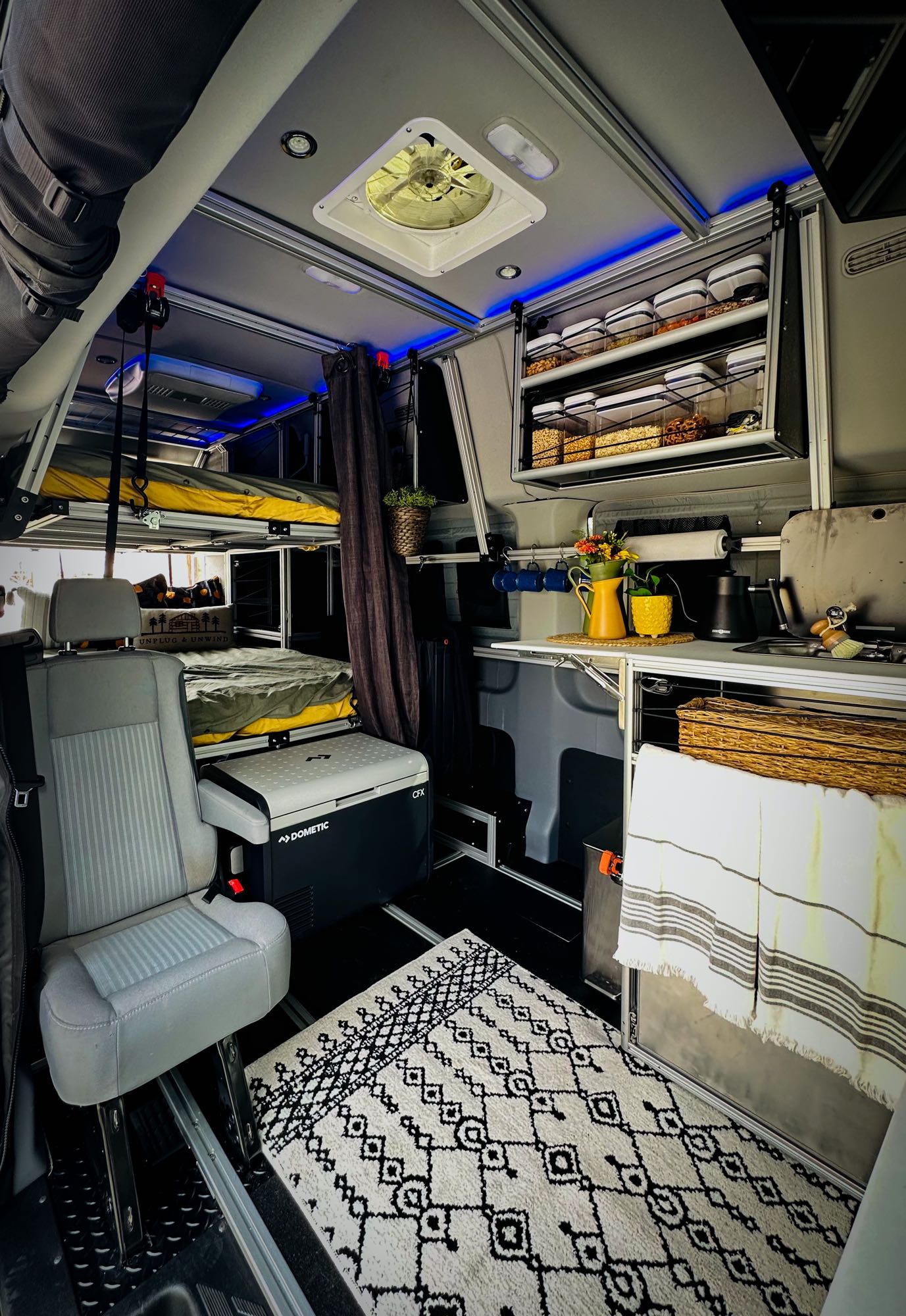 and ample space below for travel.|Explore a modern RV rental interior: functional kitchenette