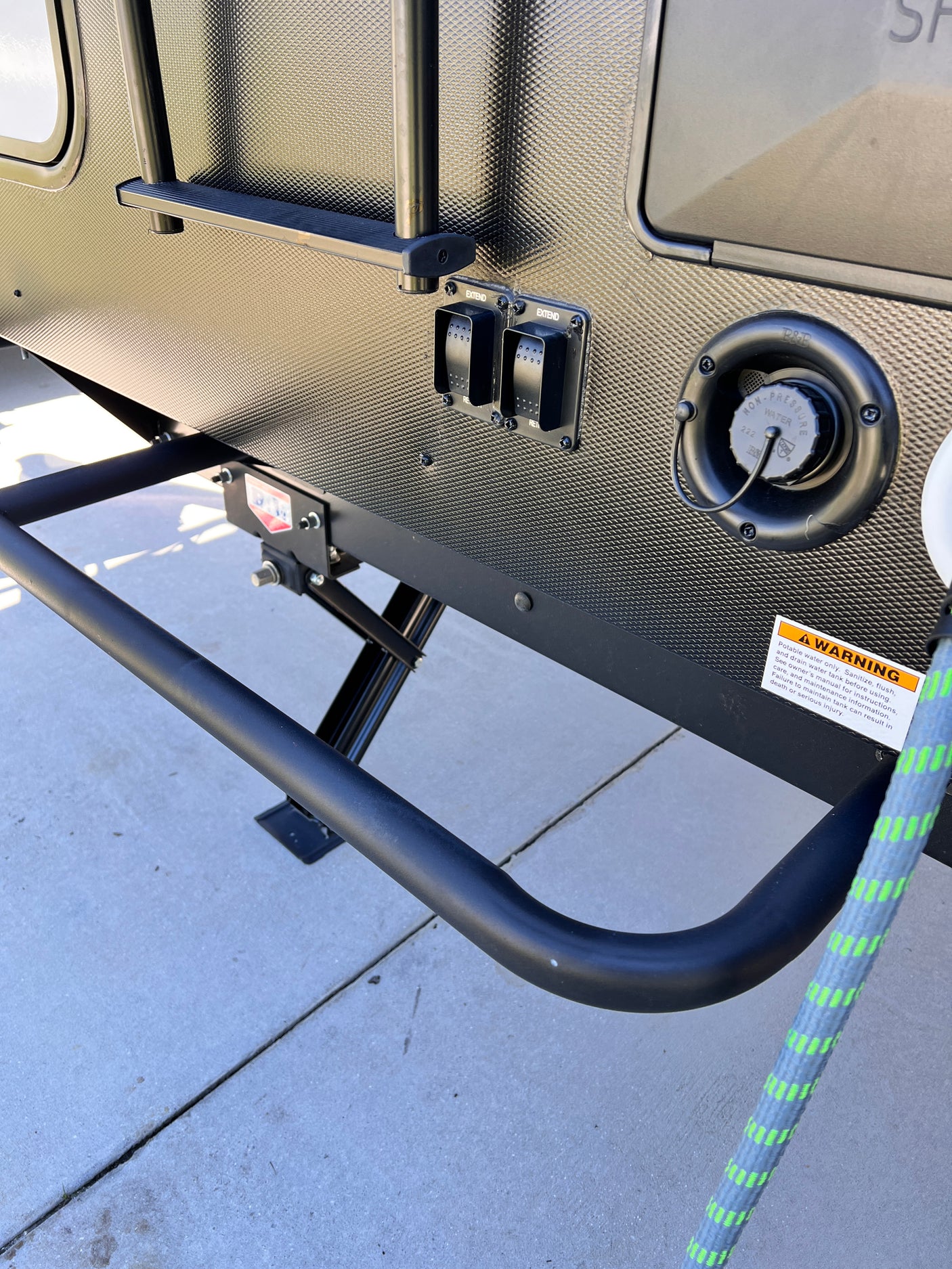RV rental exterior shows a water fill port, extend/retract switches for leveling or awning, and part of an access ladder.
