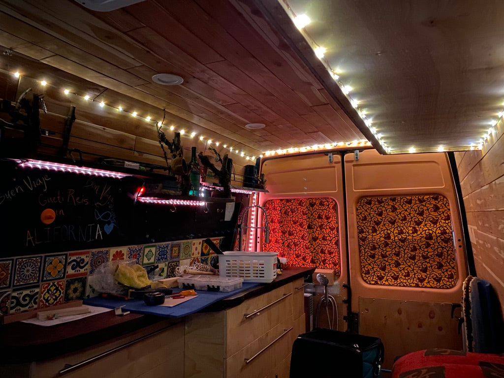 Cozy, customized RV rental interior with wood paneling, string lights, and a charming kitchenette, ready for road trips.