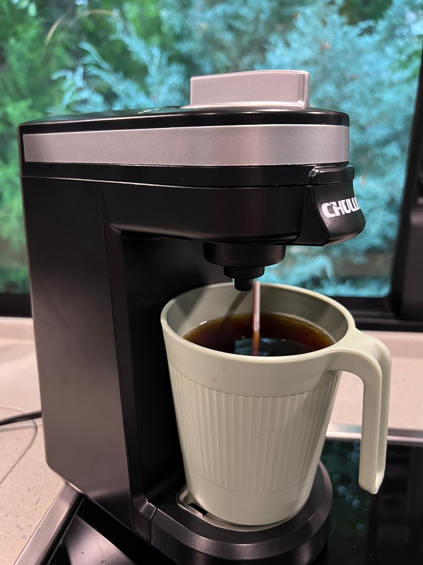A CHULUX coffee maker brews fresh coffee into a green mug, perfect for your RV rental morning adventure.