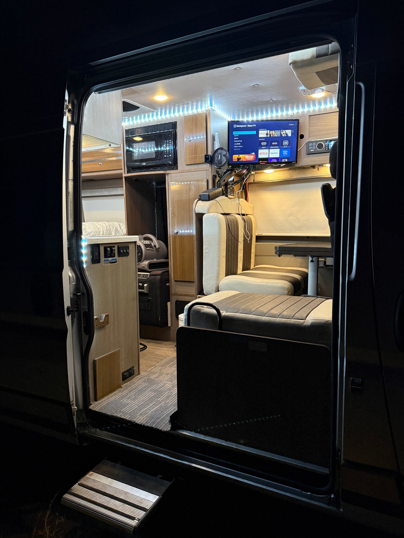 Step inside this cozy RV rental at night! Interior features include microwave, smart TV, and comfy seating.