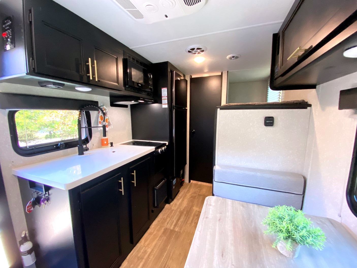 RV rental interior: modern kitchen with black cabinets, white counters, dining area, and cozy bench seating.