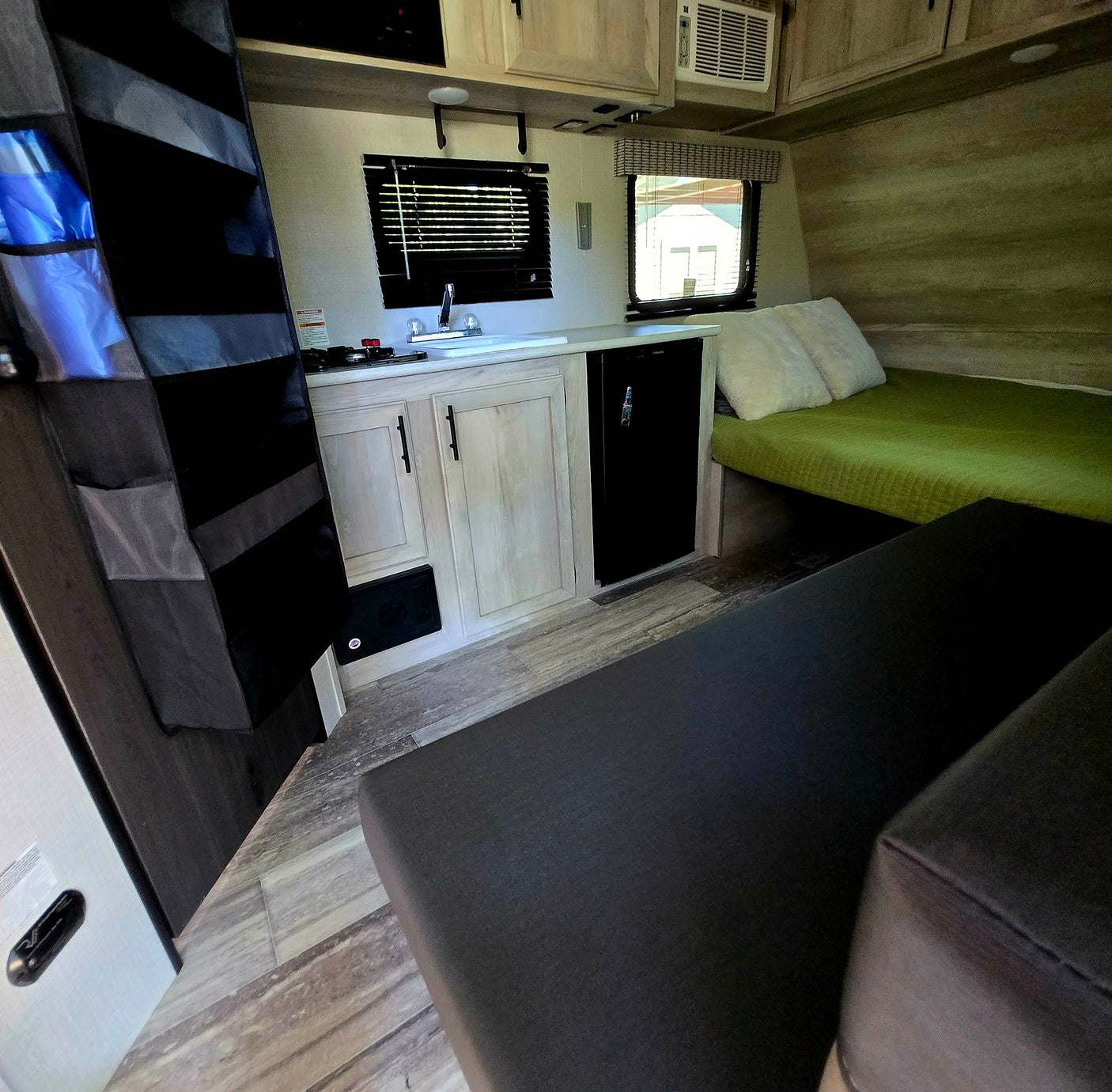 Well-appointed RV rental with a cozy bed, functional kitchenette, and comfy seating, ideal for travel adventures.