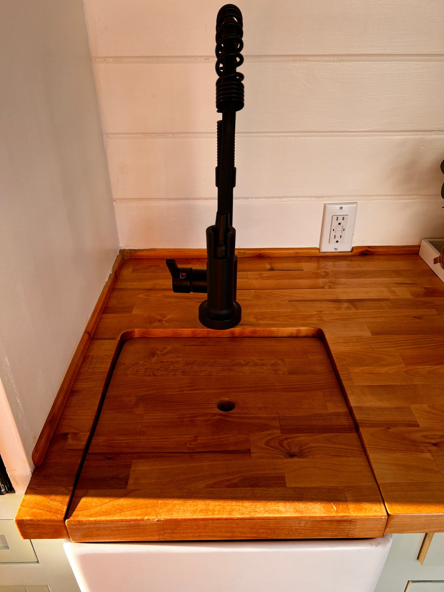 RV rental kitchen features a light wood counter, modern black faucet, and a smart, covered sink design.