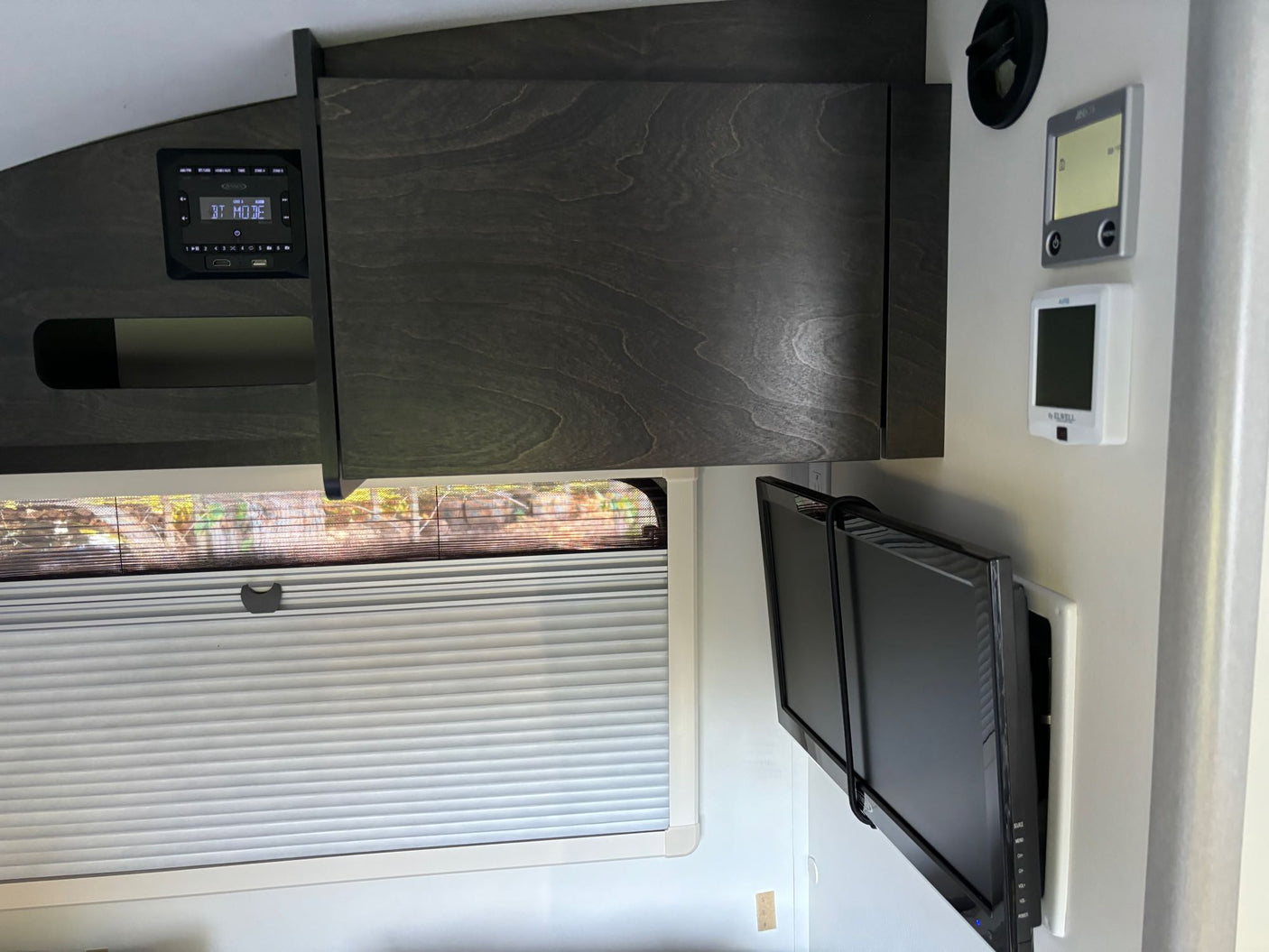 set in a peaceful forest campsite.|Modern RV rental interior: Wall-mounted TV