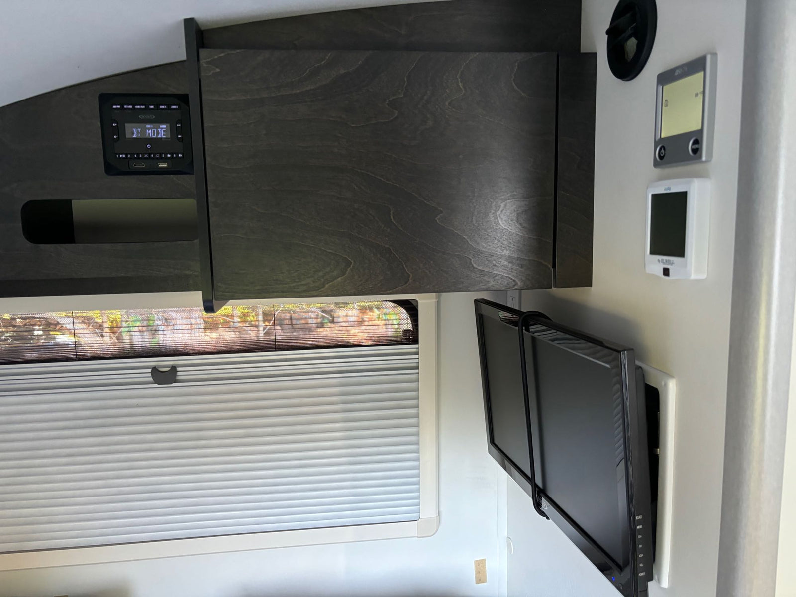 set in a peaceful forest campsite.|Modern RV rental interior: Wall-mounted TV