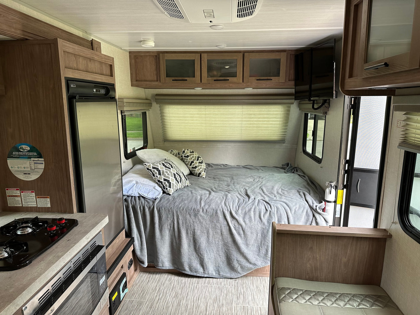 Inside an RV rental, featuring a comfortable bed, compact kitchen, overhead cabinets, and a television, ready for your trip.