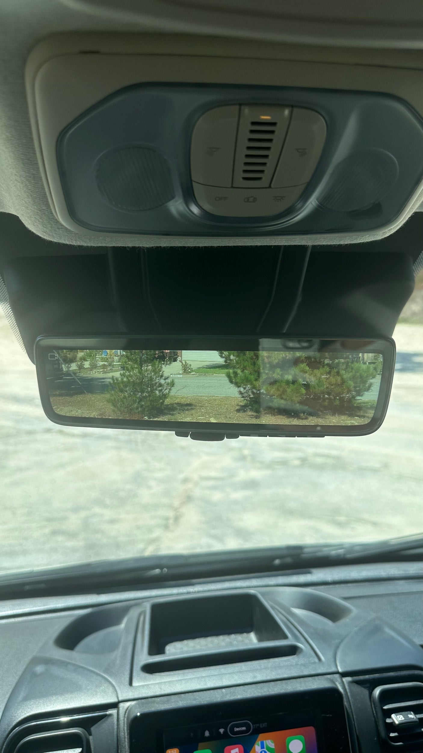 RV rental interior view: digital rearview mirror displays outdoors, dashboard and overhead controls visible.
