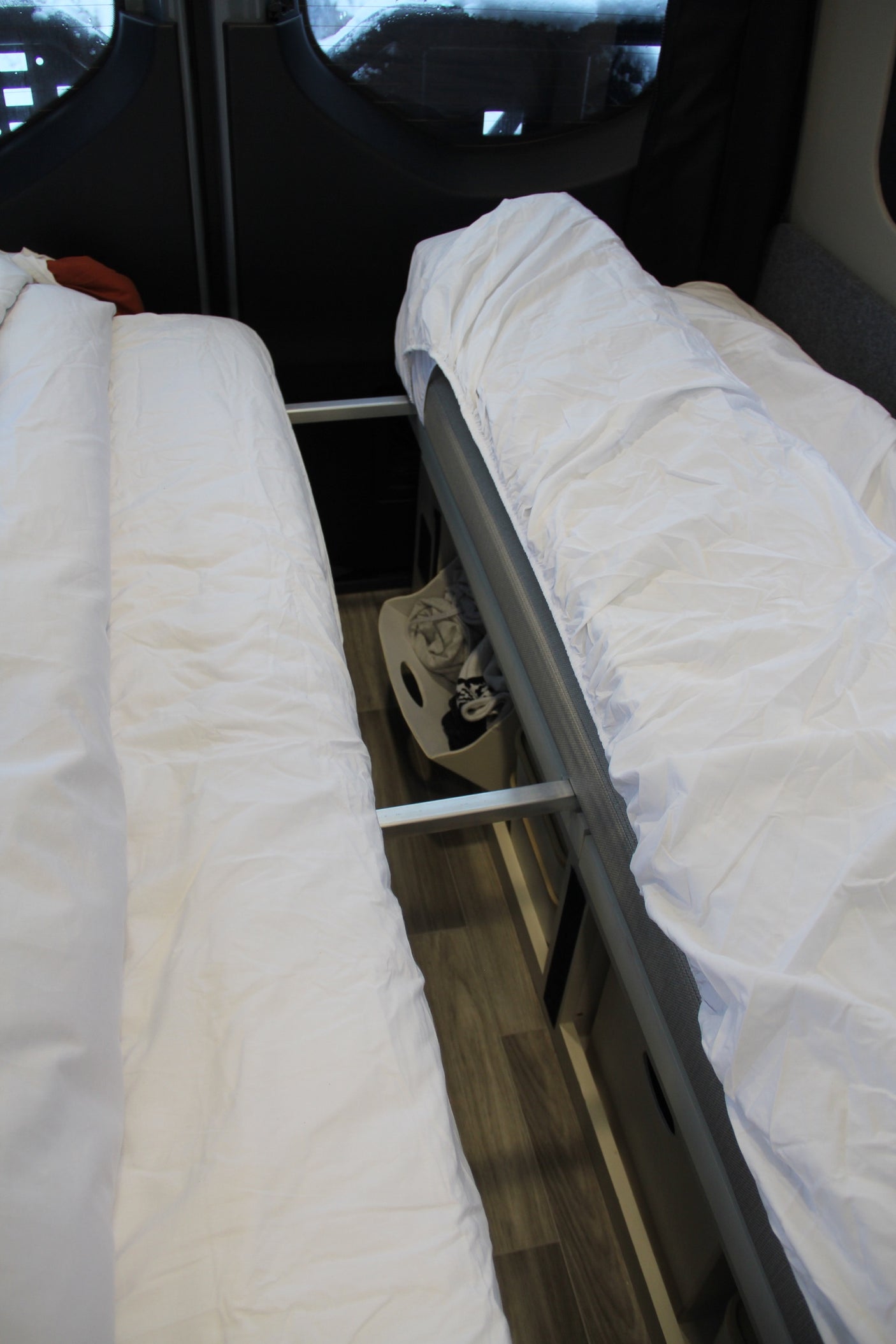 Two beds with white bedding in an RV rental, showcasing efficient interior space and accessible storage.