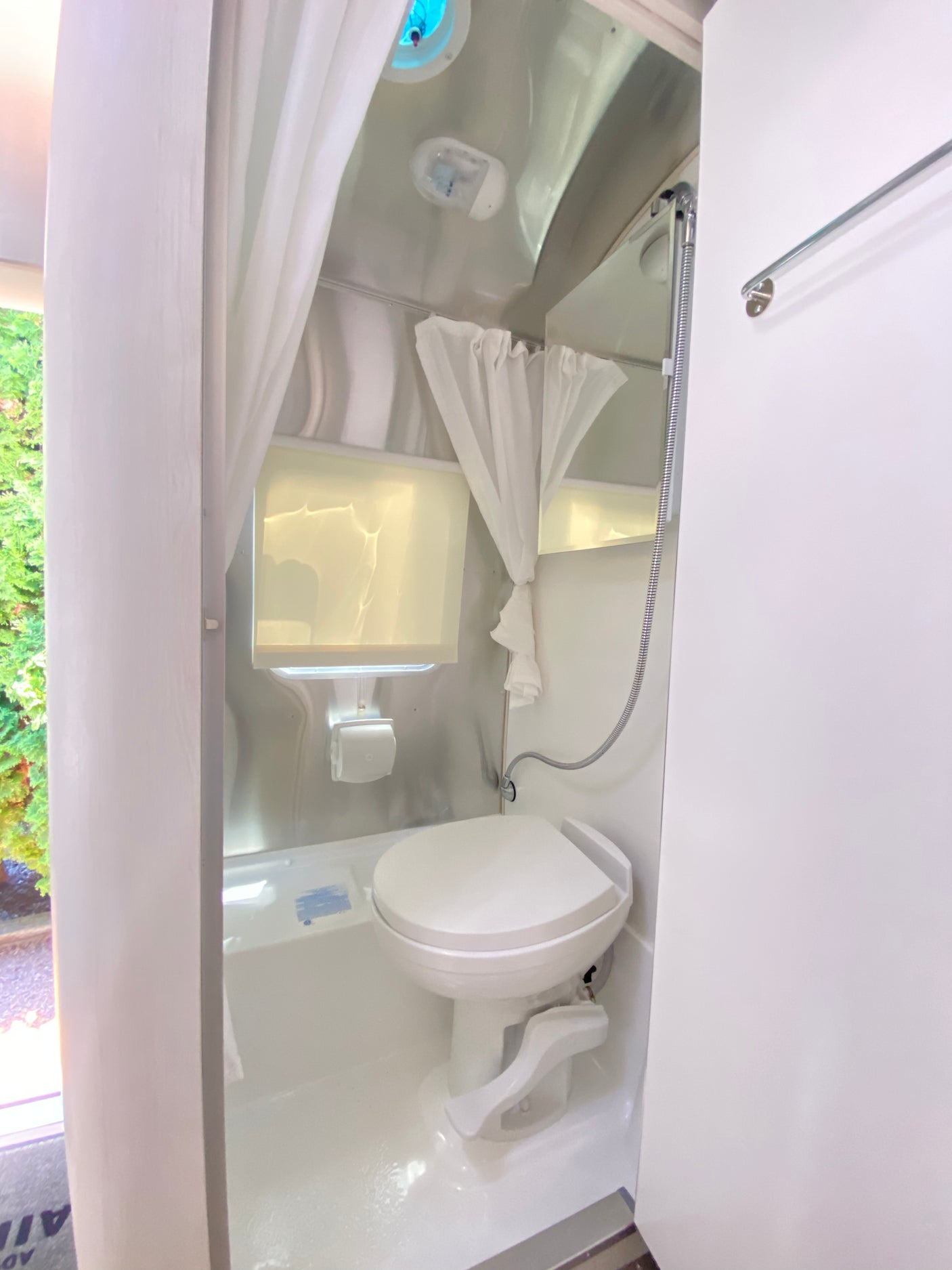 Explore the compact and efficient bathroom setup in this RV rental, with a toilet, shower, and bright interior.