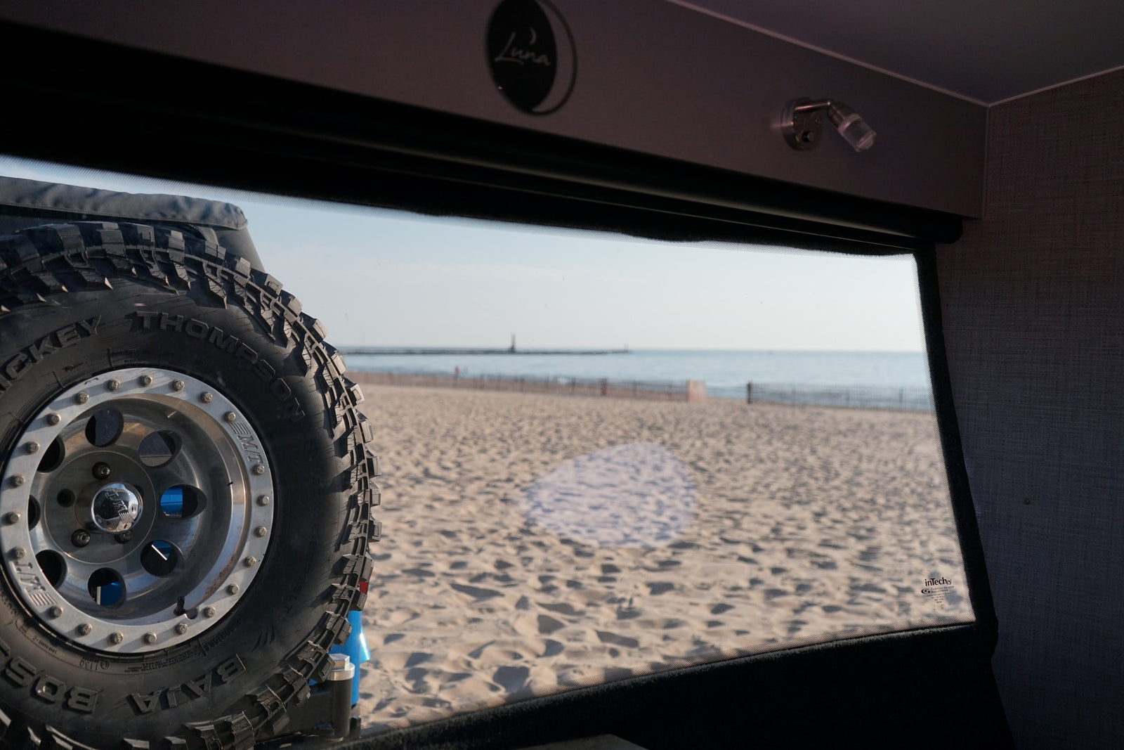 part of its convenient outdoor kitchen setup.|RV rental window view: rugged Mickey Thompson tire