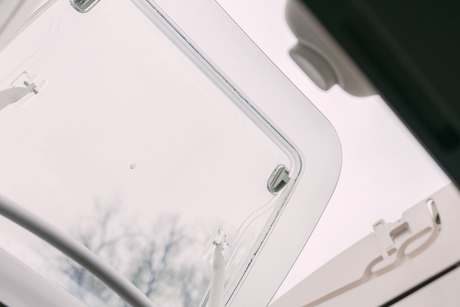 An open RV skylight provides natural light and a view of trees from inside an RV rental.