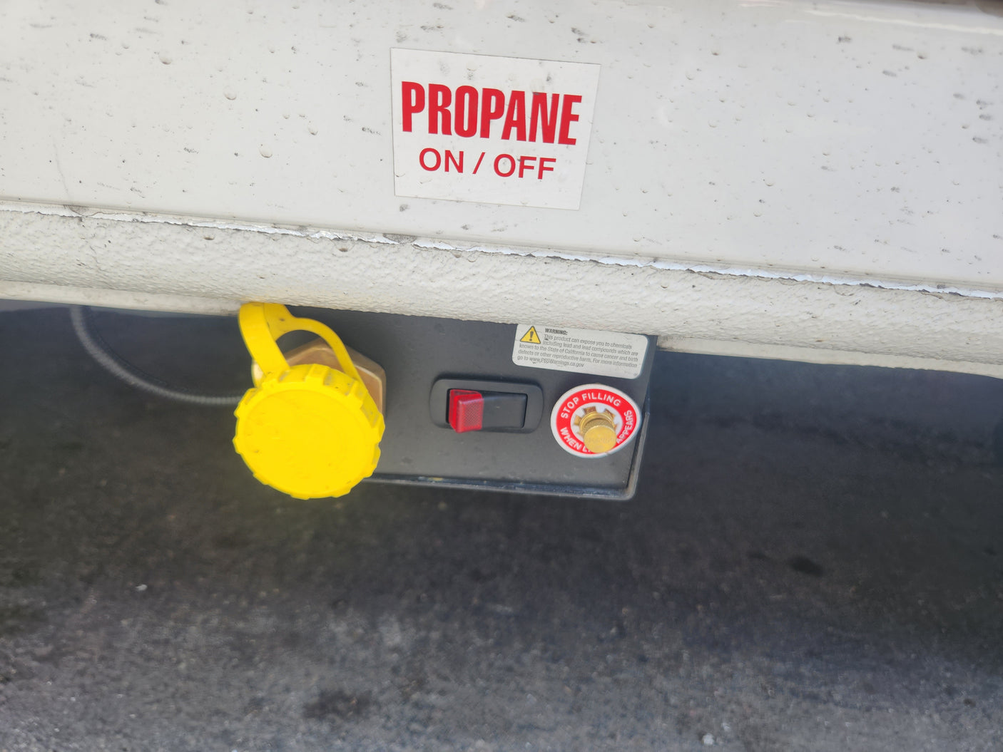 RV rental propane system: yellow fill point cap, ON/OFF switch, and safety warnings. Essential for safe RV operation.