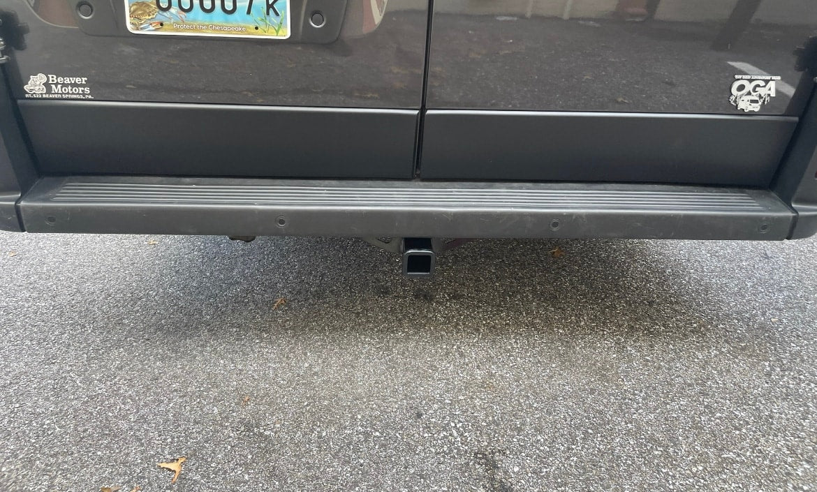 An RV rental's rear shows a tow hitch and bumper sensors, ready for adventure.
