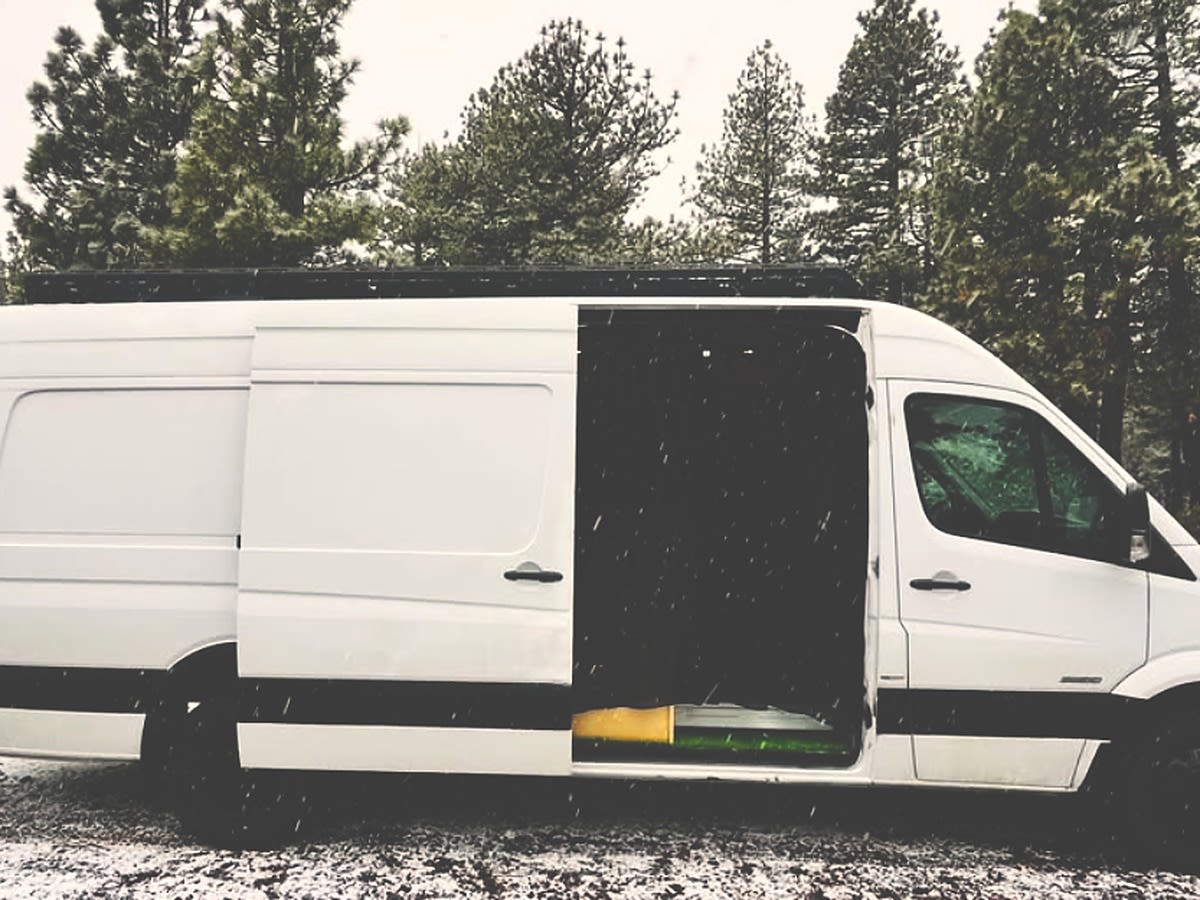 driver's door open in a snowy forest. Ideal for winter adventures and van life.|Adventure-ready rv rental camper van in a snowy forest. Open rear doors reveal a cozy — photo 7