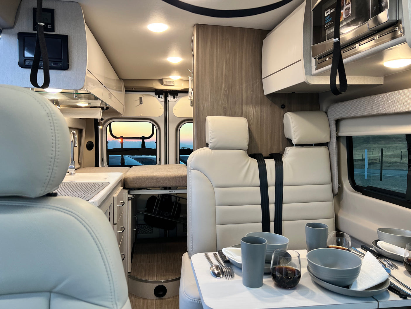 This RV rental offers a compact, bright interior with kitchen, dining area, and panoramic sunset views.