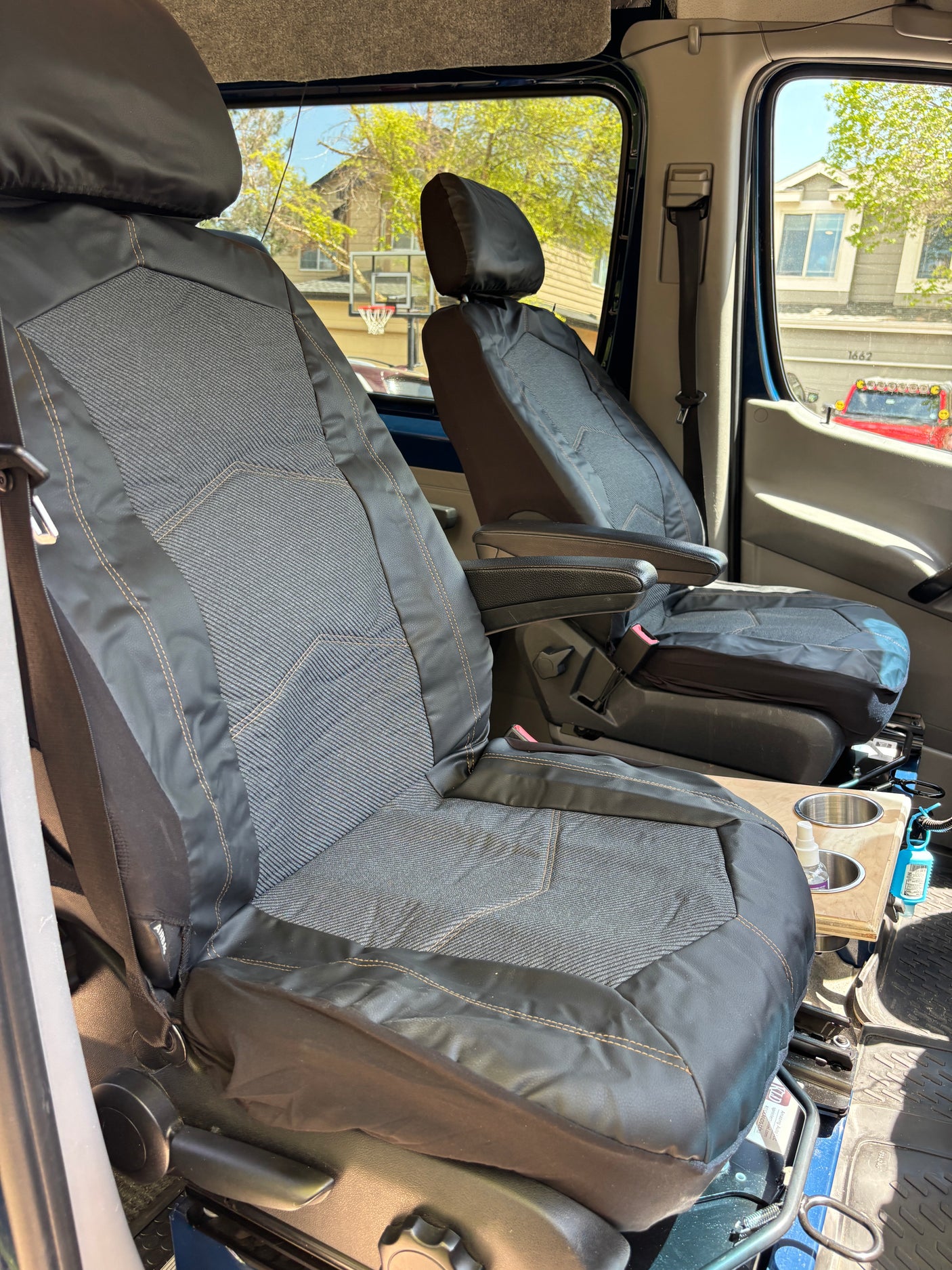 RV rental: View of the front cabin with two custom-covered seats, armrests, and center console with cup holders.