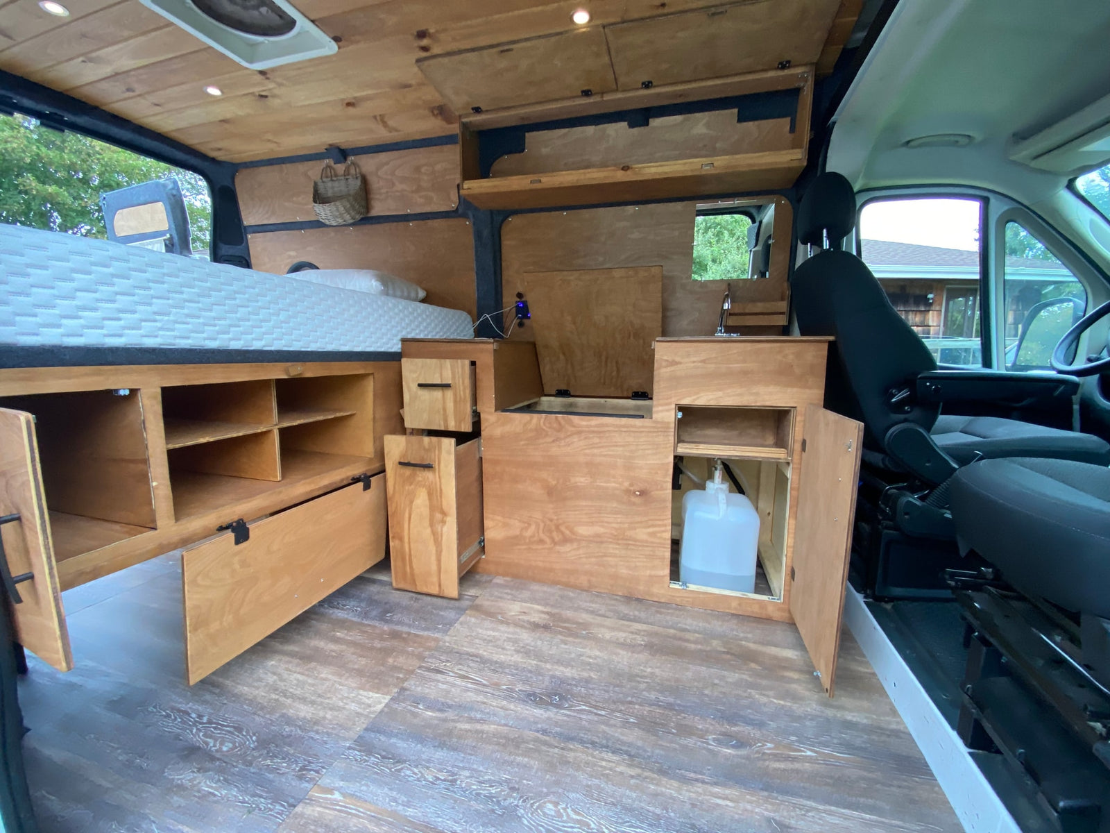 and smart storage solutions.|This RV rental interior showcases a compact camper van design: wood cabinetry