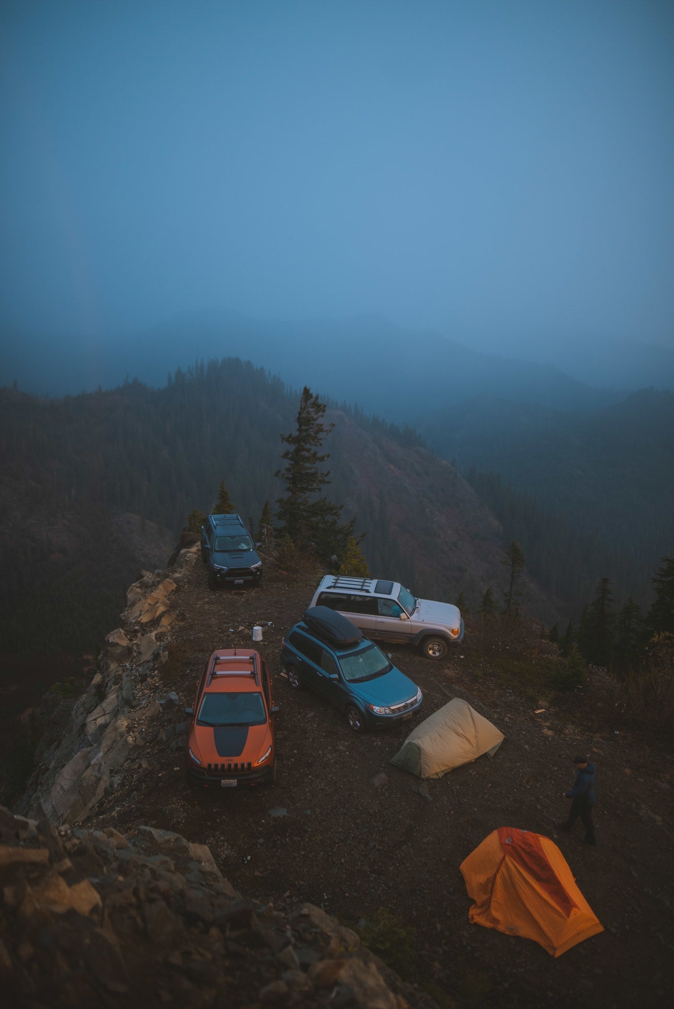 Four SUVs & two tents perched on a misty mountain cliff, overlooking forests. Rugged off-road camping is a unique adventure, unlike an RV rental. — photo 20