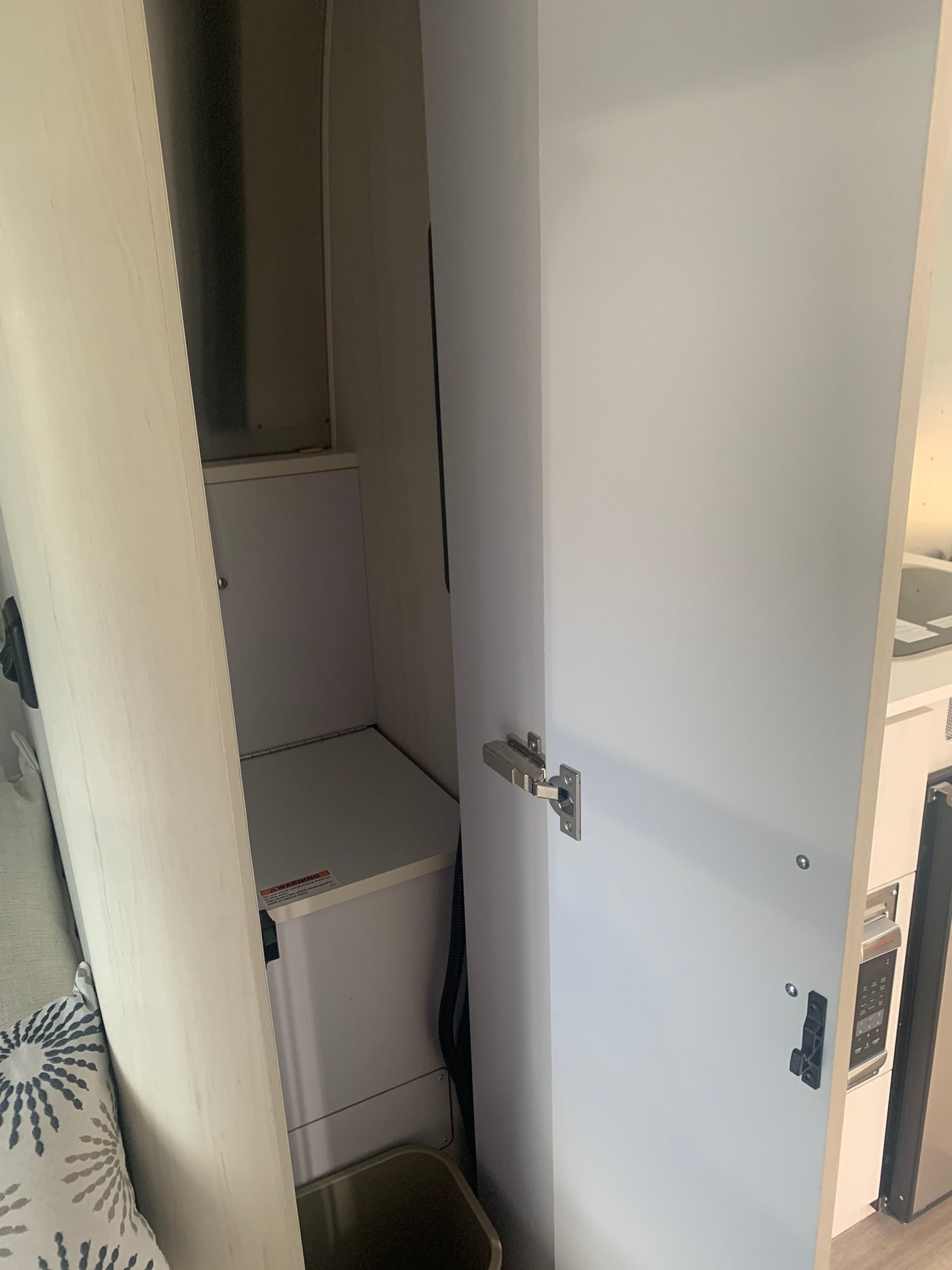 Inside an RV rental: open overhead storage cabinet revealing spacious interior, hinges, and latches. Modern kitchen area glimpse. — photo 6