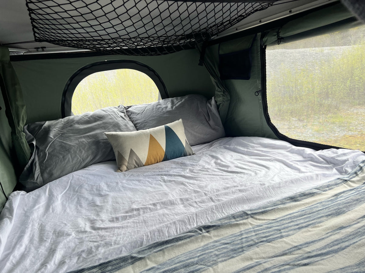 Cozy RV rental interior: a comfy bed with pillows, round window, & mesh screen for serene outdoor views. — photo 7