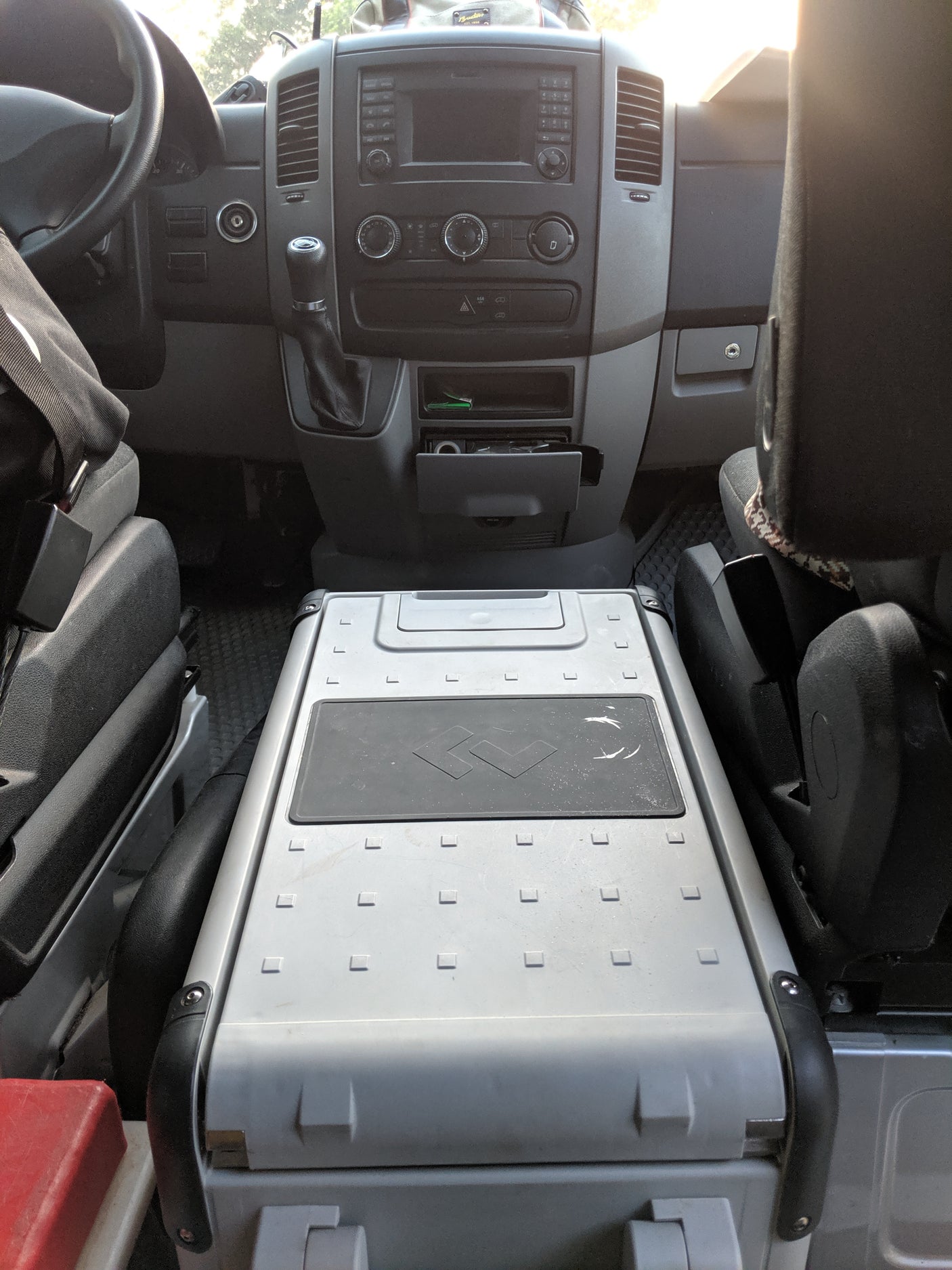 RV rental Mercedes Sprinter van interior: dashboard, steering wheel, and portable fridge between front seats.
