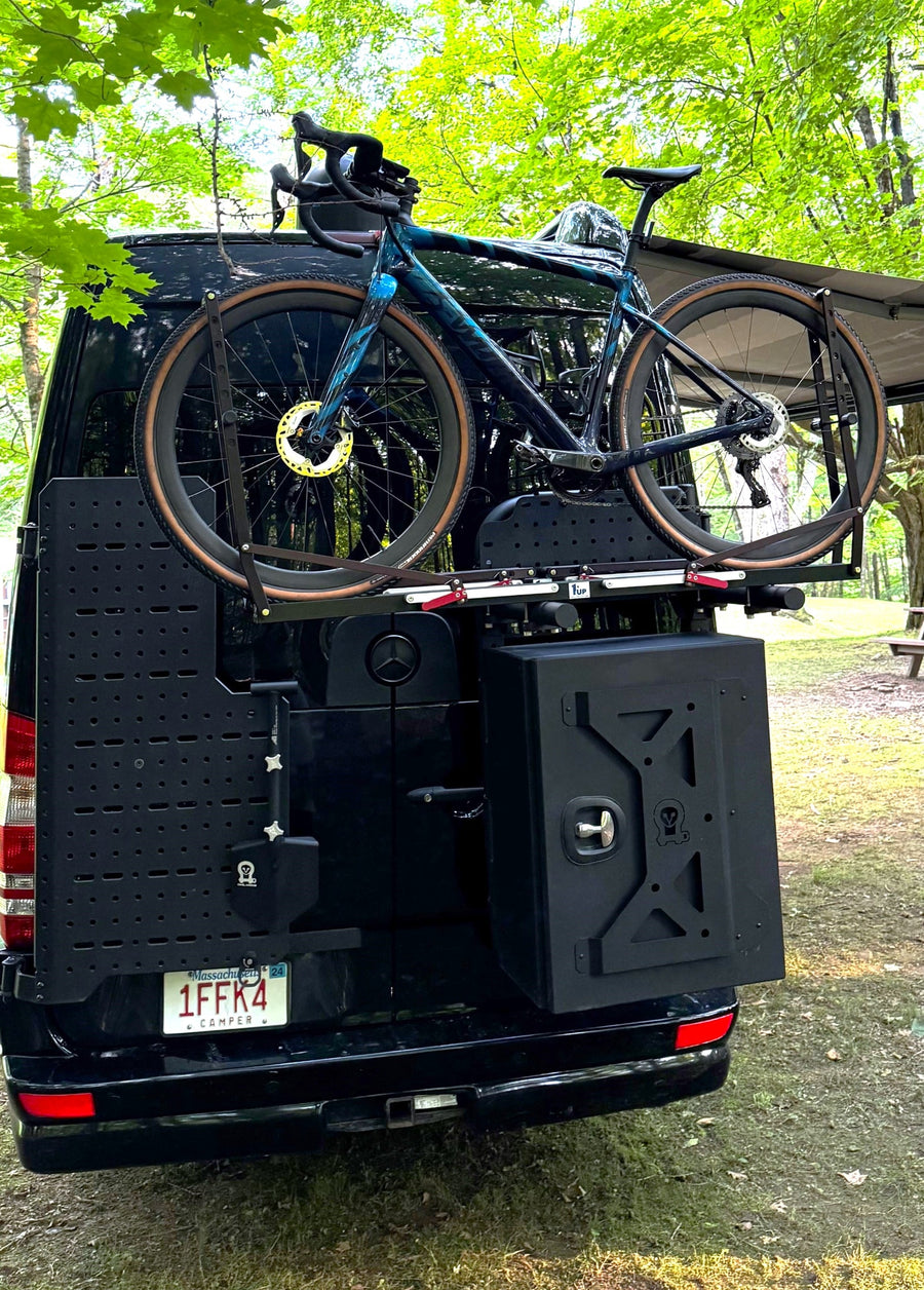 perfect for an RV rental.|Black camper van with extended awning parked in a sunny forested campsite. Perfect for your next RV rental adventure.|Black Airstream Sprinter RV rental