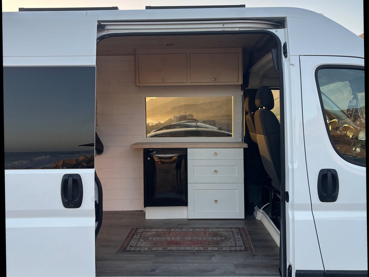 with golden skies and mountains in the distance.|This RV rental features a custom campervan kitchen — photo 2
