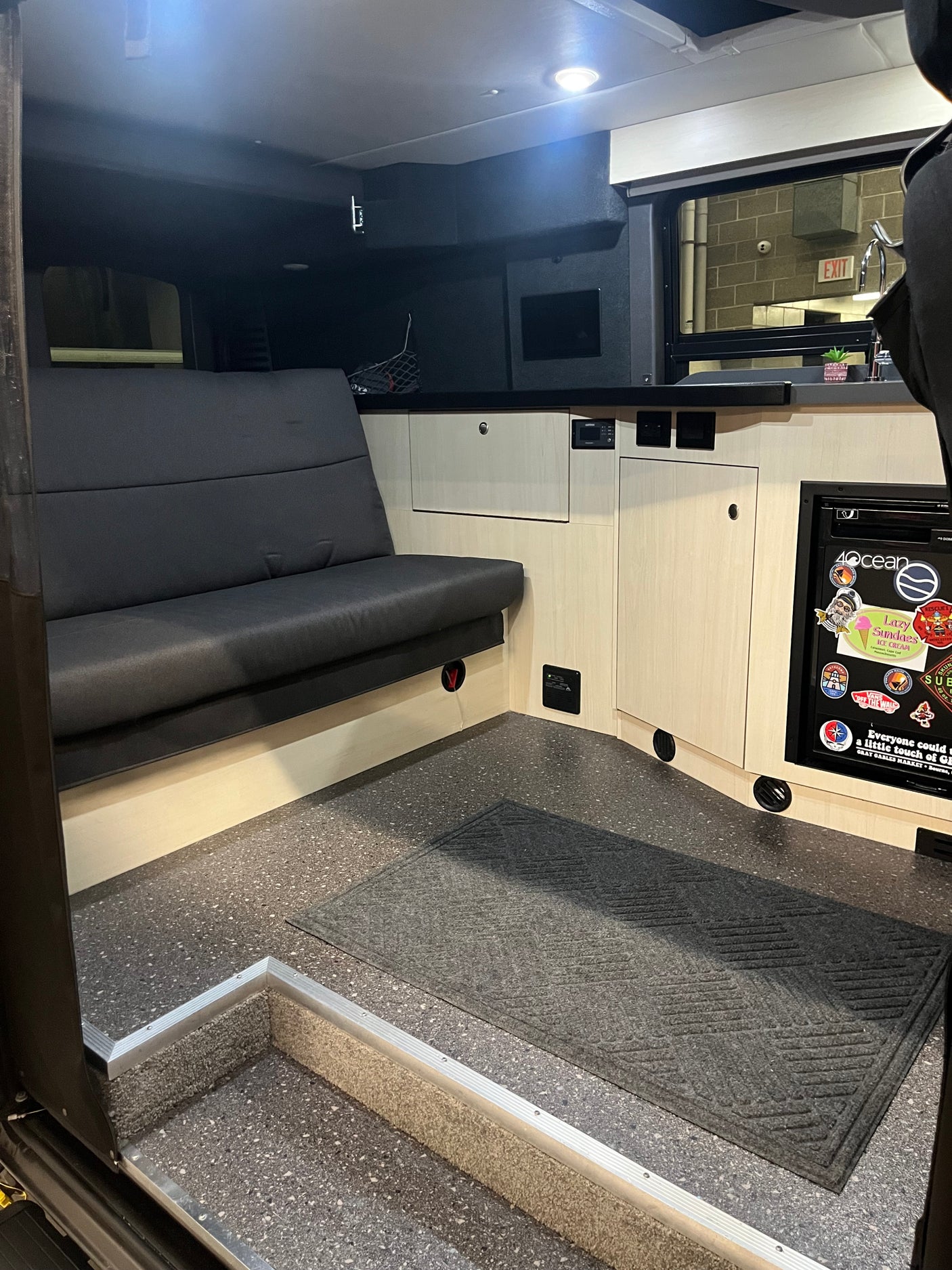RV rental interior features a dark bench seat, light wood cabinets, and a compact kitchen area with fridge.