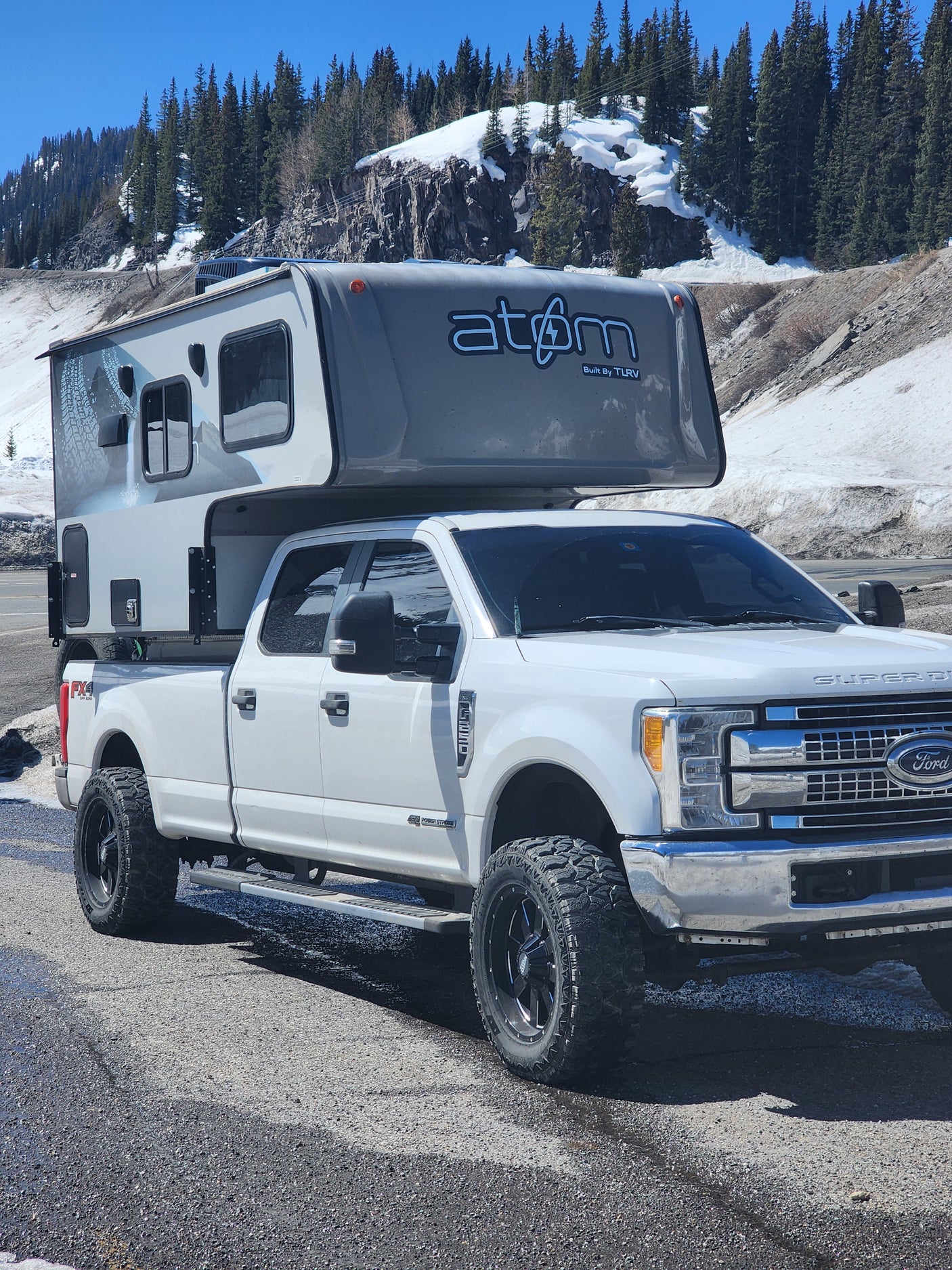 This rugged Ford Super Duty with an Atom truck camper, perfect for an RV rental adventure, is ready for mountain exploring.