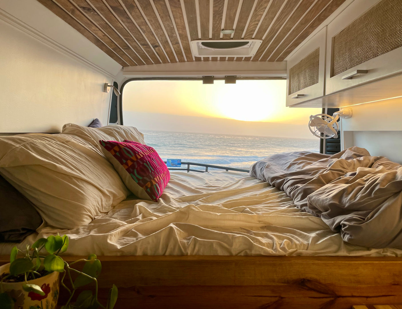 Cozy RV rental bedroom with a stunning ocean sunset view. Ideal for van life adventures on the road.