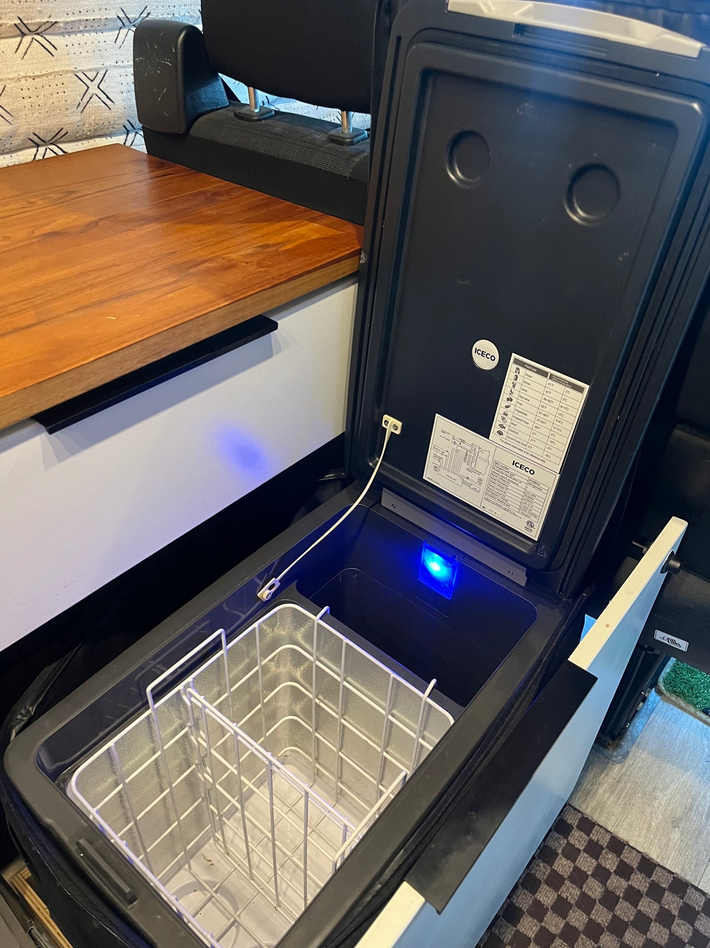 An open ICECO portable fridge/freezer with an internal basket and blue light, perfect for an RV rental adventure.