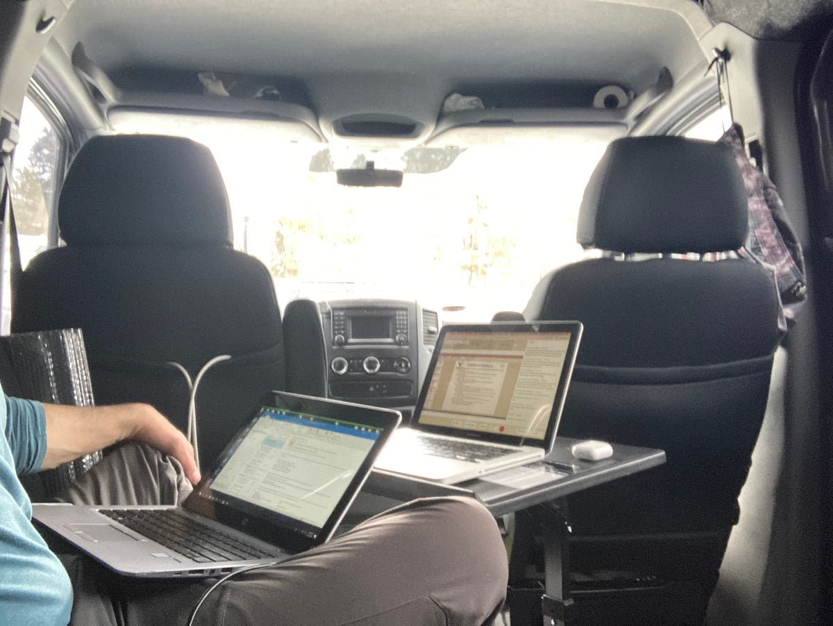 Interior view of an RV rental: Two people work on laptops inside a van, set up as a mobile office. — photo 10