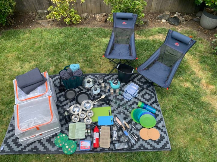 Essential gear for your RV rental adventure! This photo displays chairs, kitchenware, and camping supplies neatly arranged on a mat outdoors.