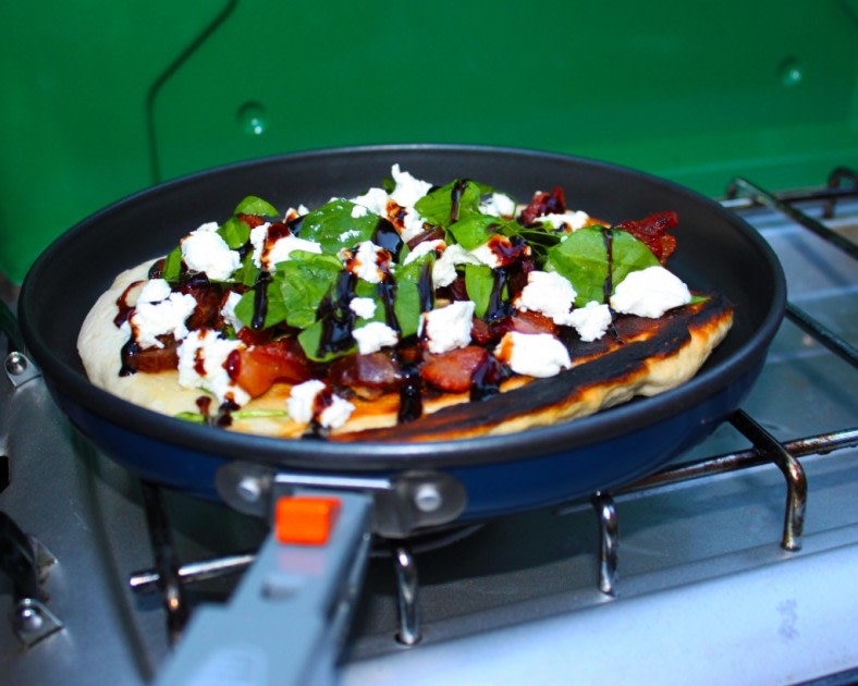 Delicious pan-cooked flatbread pizza with feta, spinach, and balsamic glaze on a portable stove, perfect for RV rental trips.